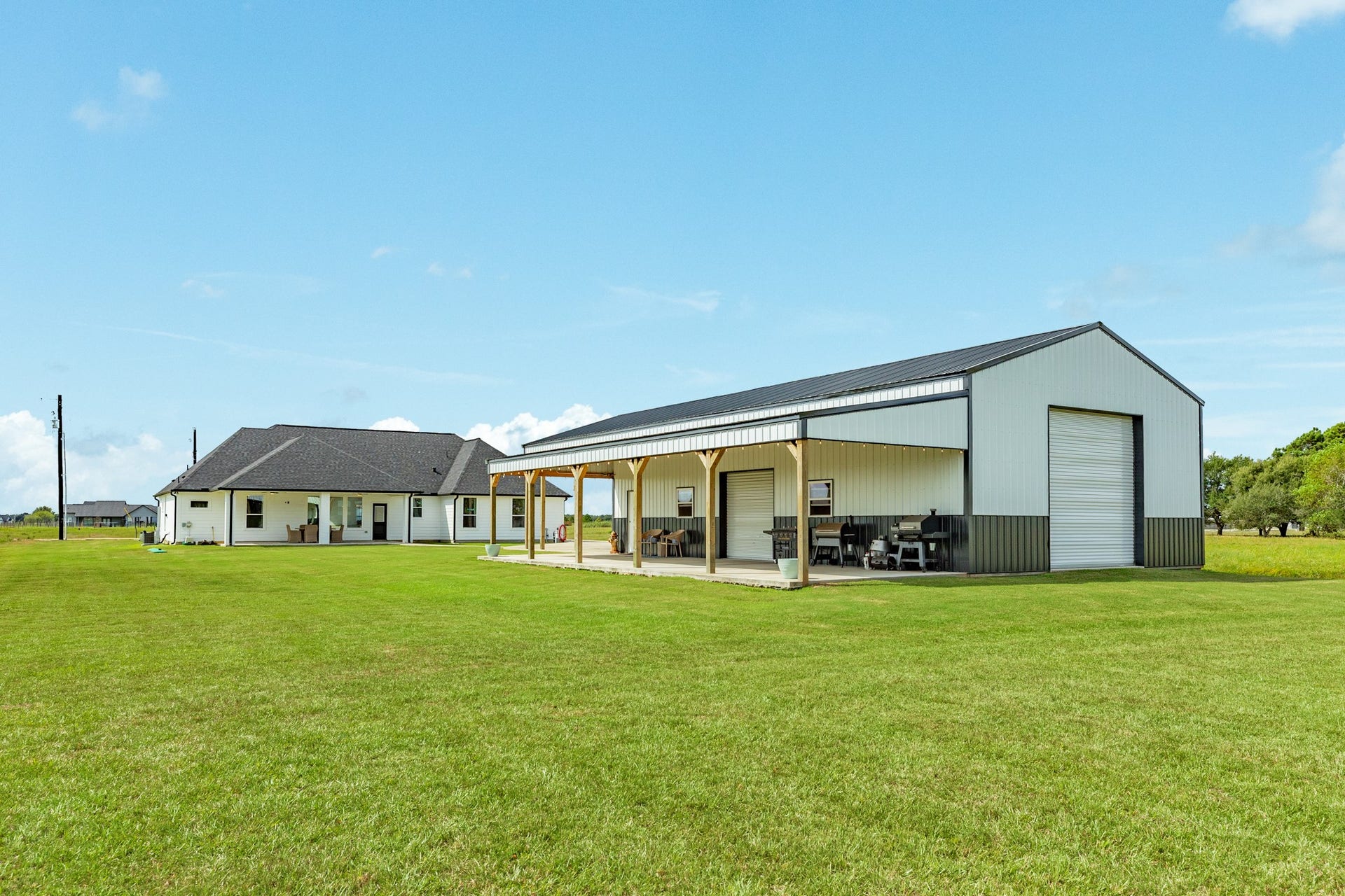 608 Angus Trail, Angleton, TX 77515 View from behind the workshop. Notice the additional roll-up door on the back of the shop for easy access to lawn and garden maintenance items