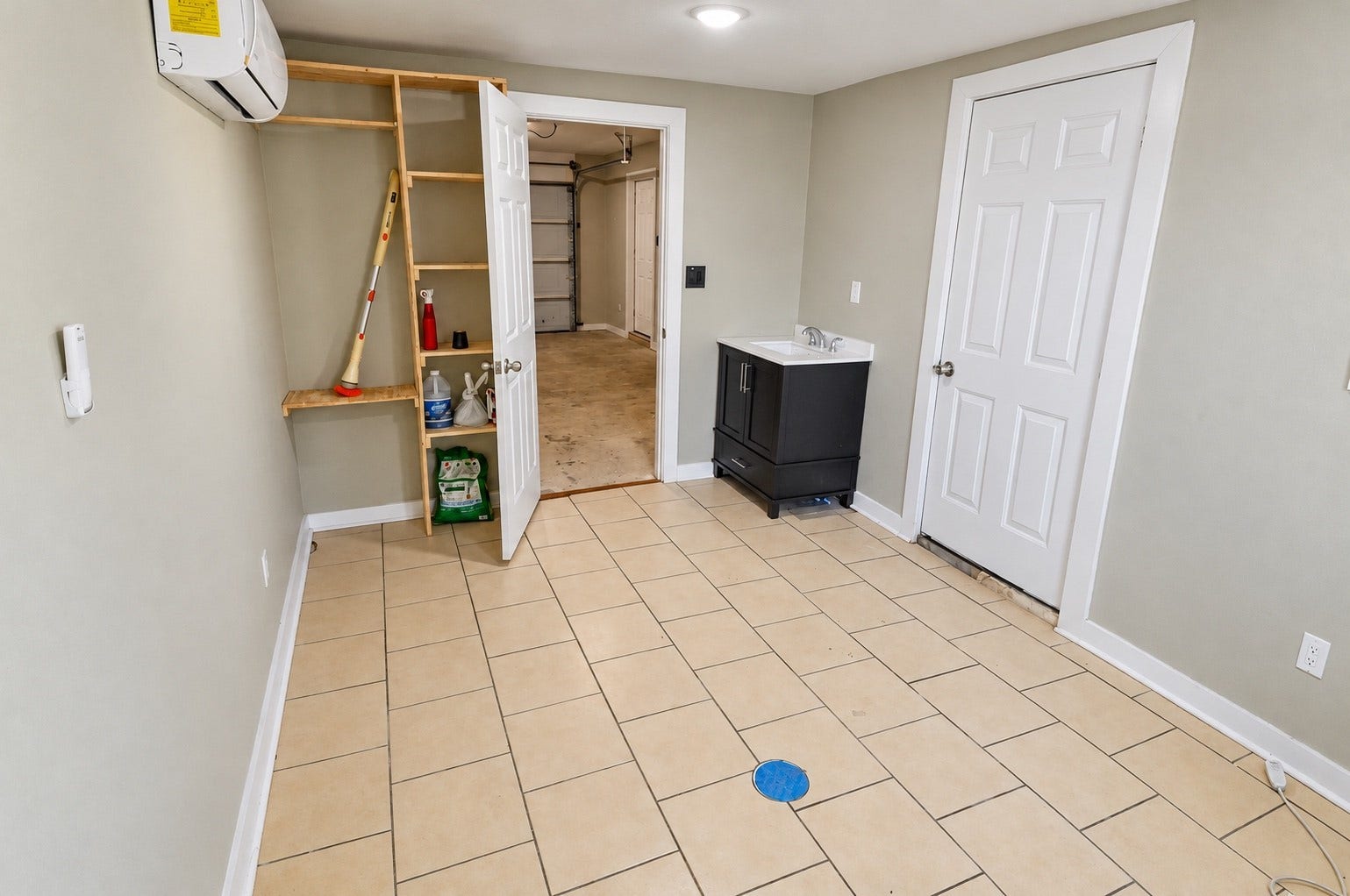 1837 Wycliffe Drive, Houston, TX 77043 Spacious utility room featuring tiled floors, a compact sink, storage shelves, and access to the garage.