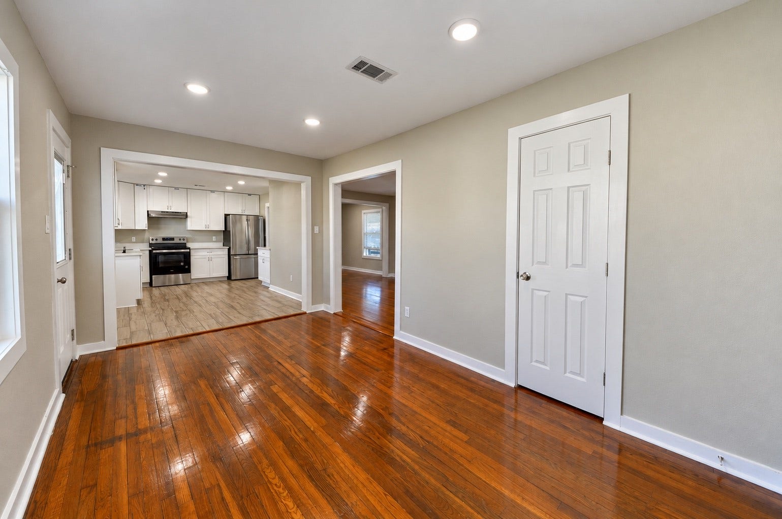 1837 Wycliffe Drive, Houston, TX 77043 Charming living area with gleaming hardwood floors and recessed lighting, leading to a modern kitchen with stainless steel appliances and white cabinetry.