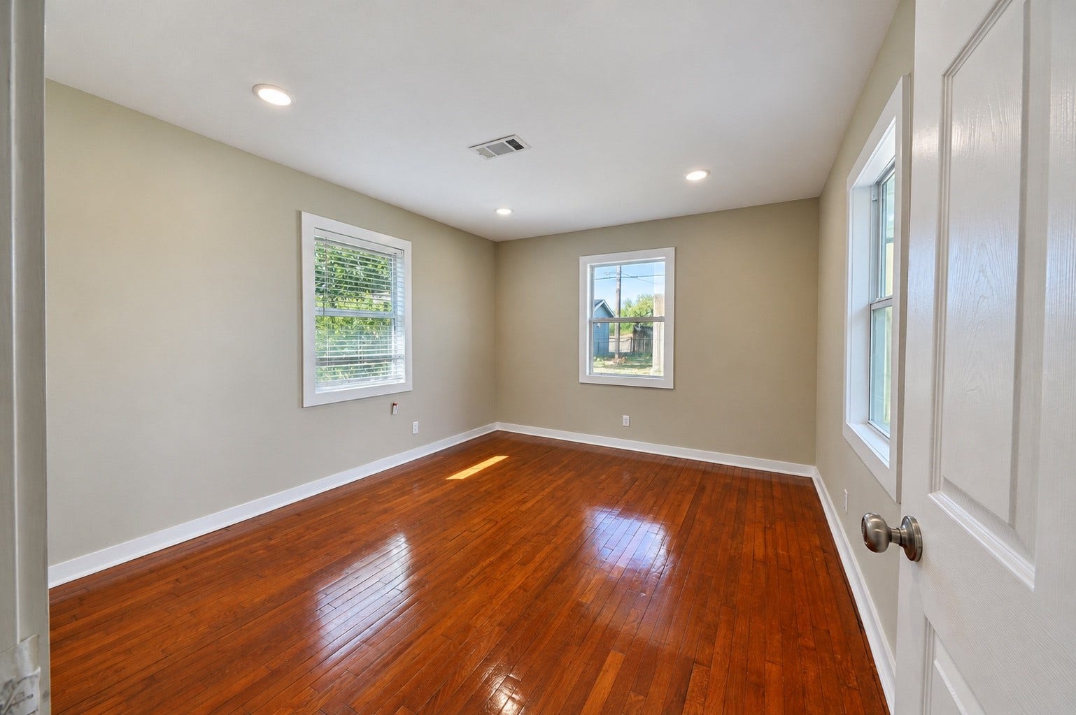 1837 Wycliffe Drive, Houston, TX 77043 Sunlit room with gleaming hardwood floors, neutral walls, and large windows offering a bright, inviting atmosphere.