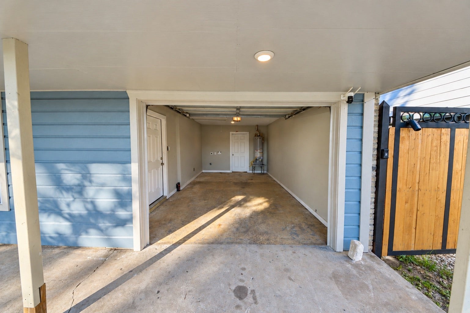 1837 Wycliffe Drive, Houston, TX 77043 A spacious garage with clean lines and ample lighting, featuring a secure wooden gate and convenient interior access.