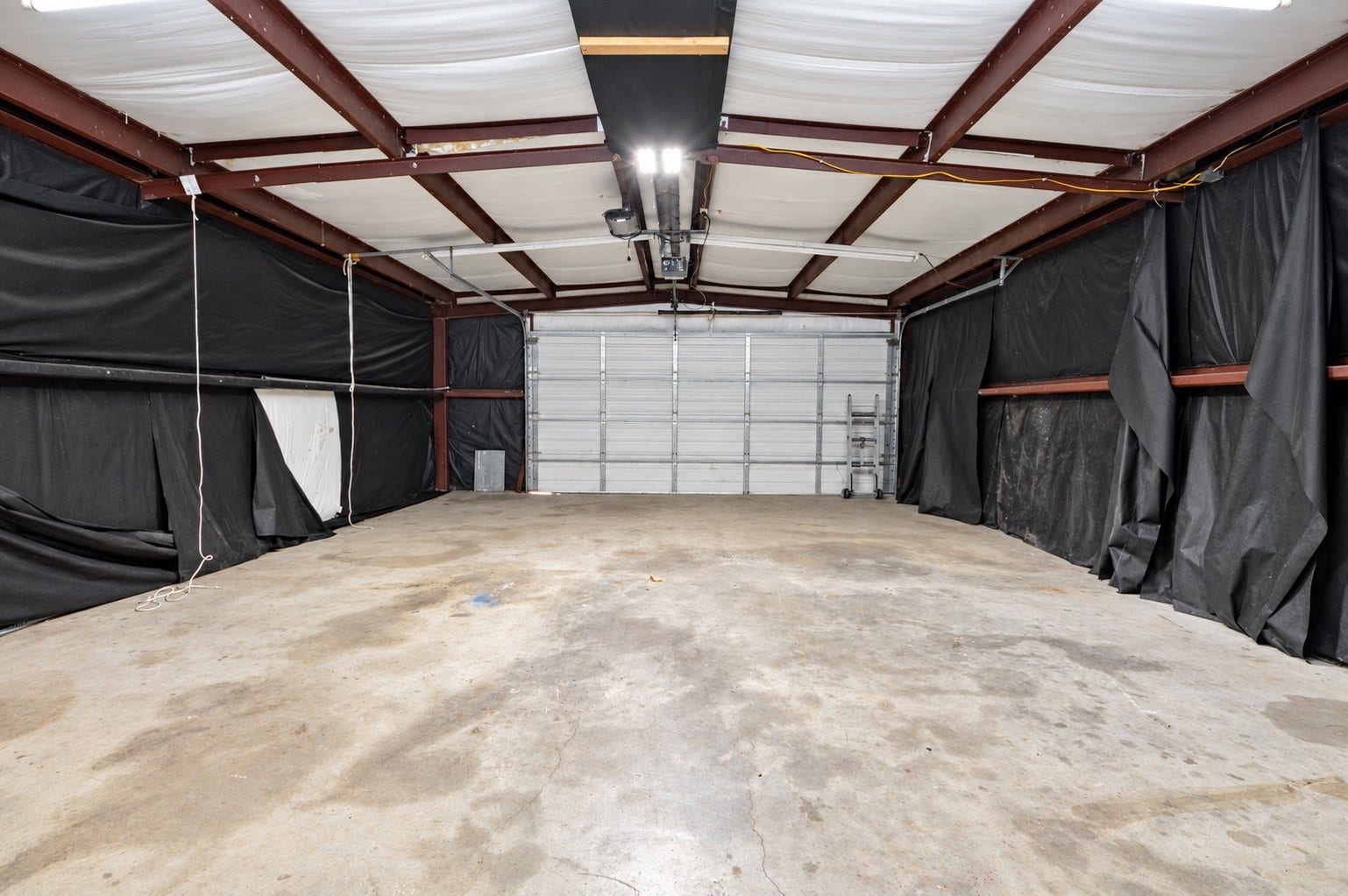 1837 Wycliffe Drive, Houston, TX 77043 Spacious garage with high ceilings and ample room for vehicles or storage, featuring a large roll-up door for easy access.