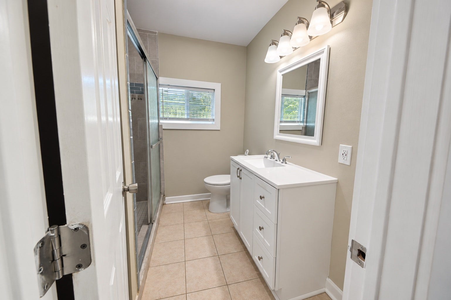 1837 Wycliffe Drive, Houston, TX 77043 Modern bathroom featuring a sleek vanity with ample storage, a large mirror, and a glass-enclosed shower, complemented by stylish lighting and neutral tile flooring.