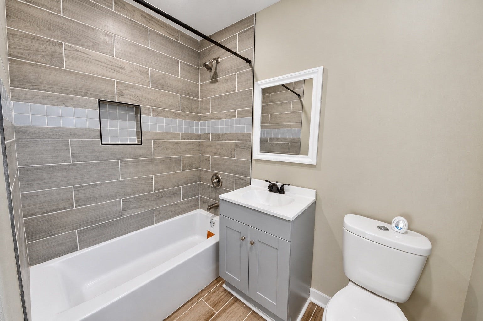 1837 Wycliffe Drive, Houston, TX 77043 Charming bathroom with modern wood-look tile, a sleek vanity with a framed mirror, and a convenient shower-tub combination.