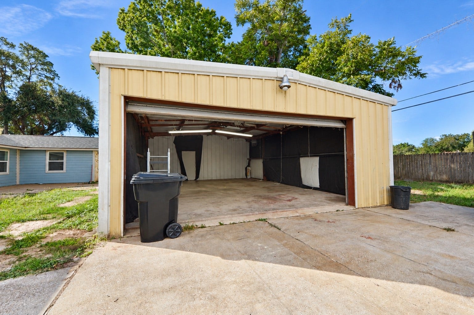 1837 Wycliffe Drive, Houston, TX 77043 Spacious metal garage with ample room for storage or parking, set on a concrete driveway with surrounding greenery.