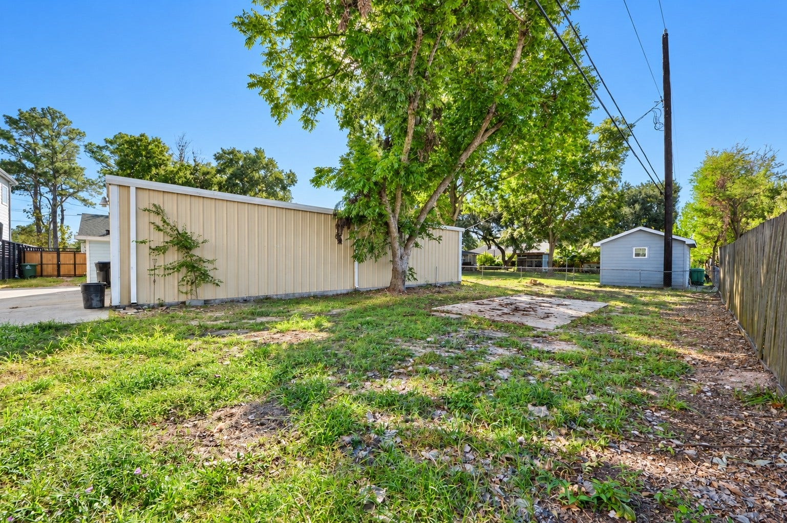 1837 Wycliffe Drive, Houston, TX 77043 Spacious backyard featuring lush greenery, mature trees, and a concrete pad, perfect for outdoor activities and gardening or additional large vehicle parking.