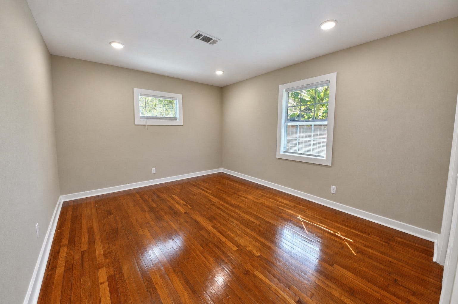1837 Wycliffe Drive, Houston, TX 77043 Bright and airy room featuring sleek hardwood floors, neutral walls, and ample natural light from two windows, perfect for a cozy bedroom or home office.