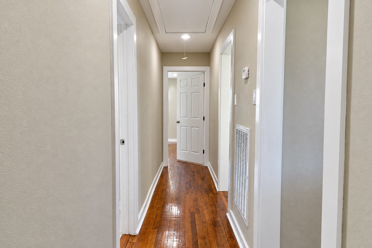 1837 Wycliffe Drive, Houston, TX 77043 Bright and inviting hallway with polished hardwood floors and soft neutral walls, leading to a well-lit interior door.