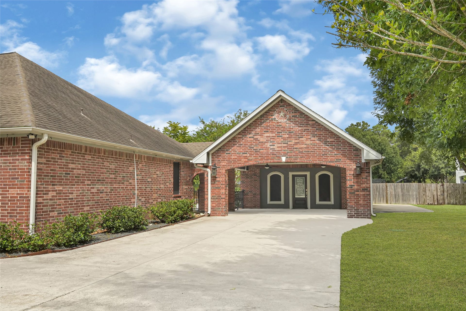 19763 Irenell Dr, Porter, TX 77365 Charming brick home featuring a welcoming portico, spacious driveway, and lush greenery, offering both style and functionality.