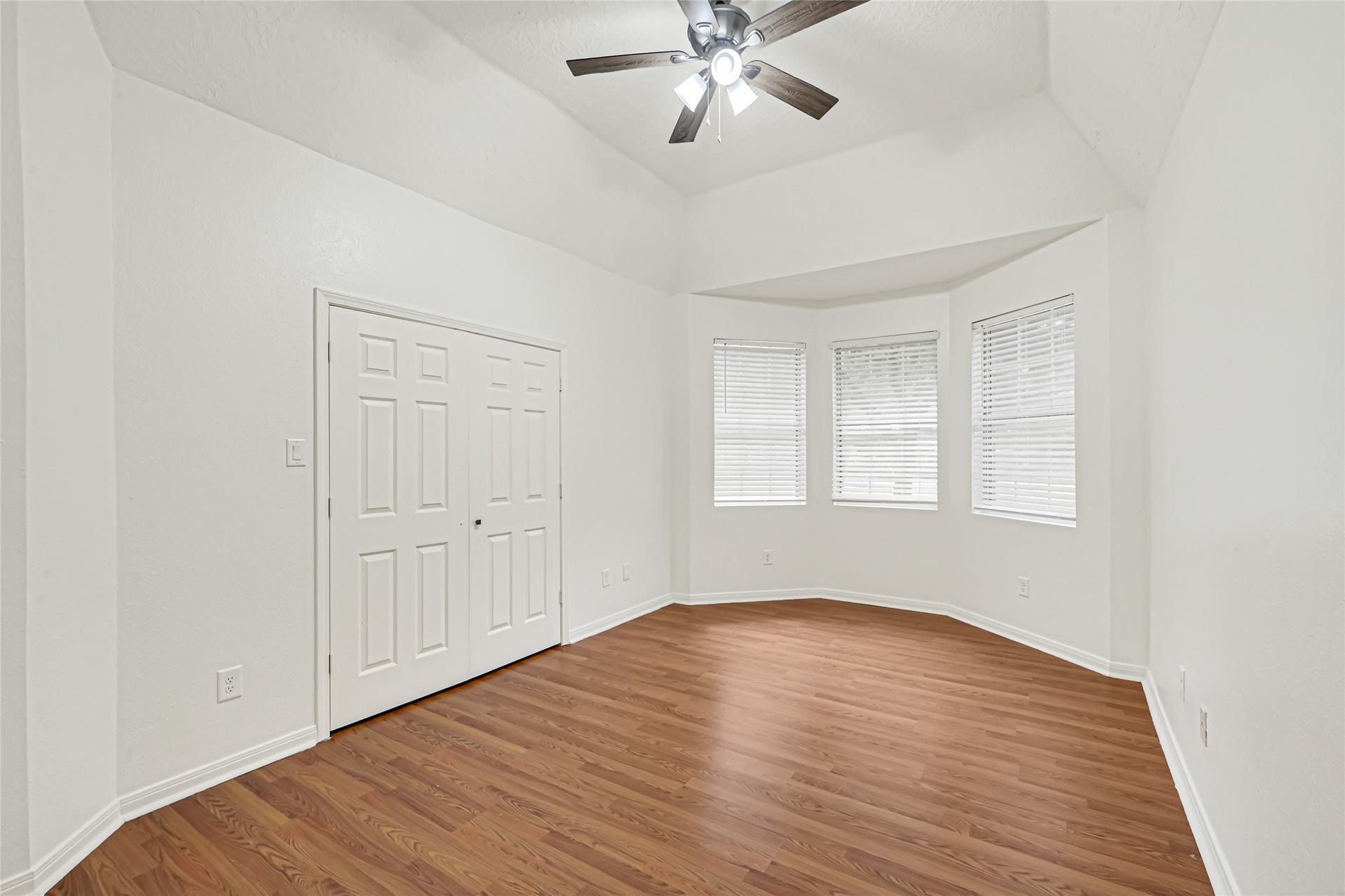 19763 Irenell Dr, Porter, TX 77365 Bright and spacious room featuring a vaulted ceiling, elegant wood flooring, and a charming bay window, complemented by a ceiling fan and ample closet space.