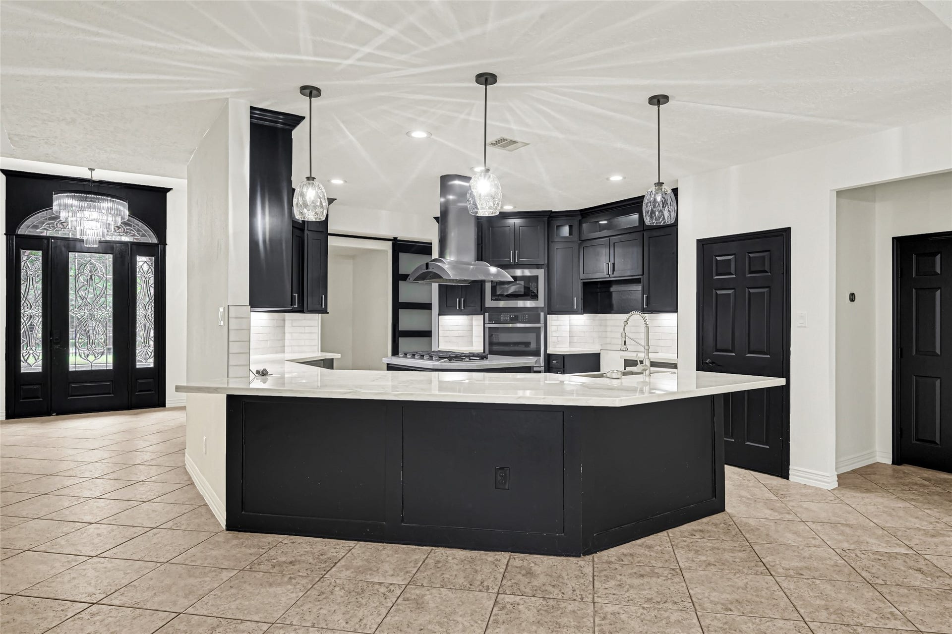 19763 Irenell Dr, Porter, TX 77365 Elegant kitchen featuring sleek black cabinetry, a spacious island with a modern sink, and stylish pendant lighting.