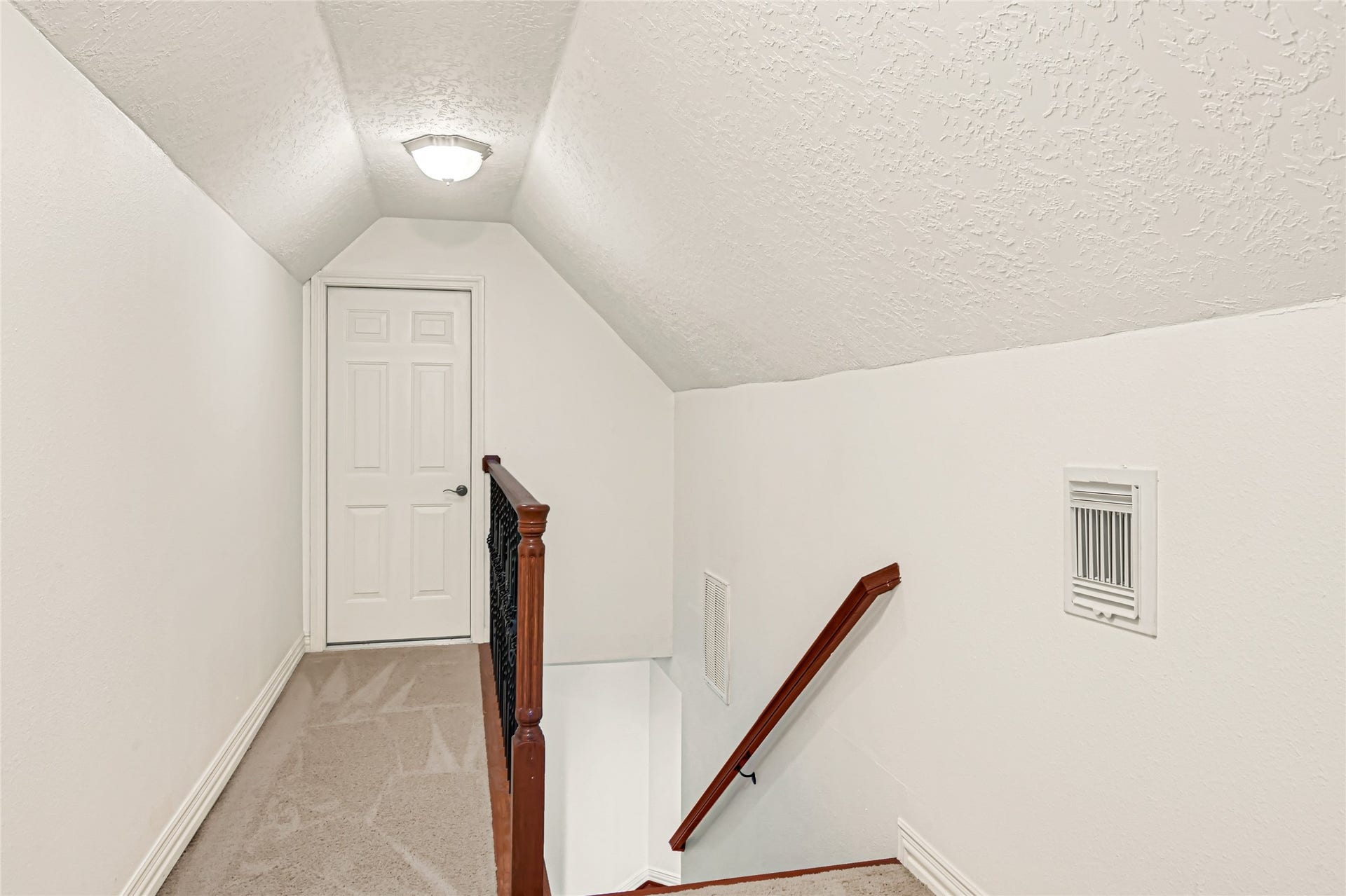 19763 Irenell Dr, Porter, TX 77365 Bright and clean hallway with a carpeted floor and a staircase featuring a wooden handrail, leading to a closed door.