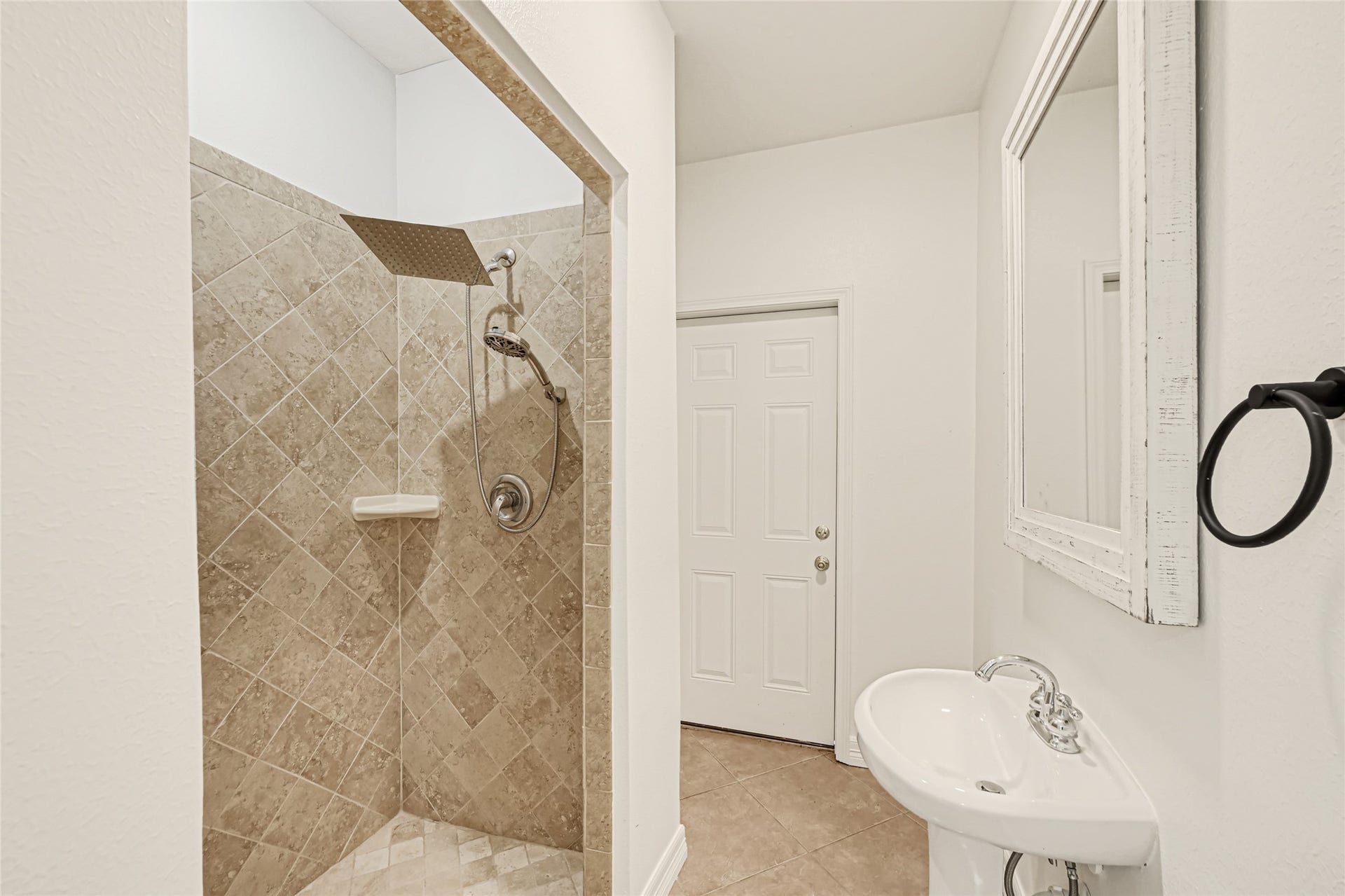 19763 Irenell Dr, Porter, TX 77365 Bright bathroom featuring a spacious walk-in shower with stylish tilework and a sleek pedestal sink, complemented by a large mirror.