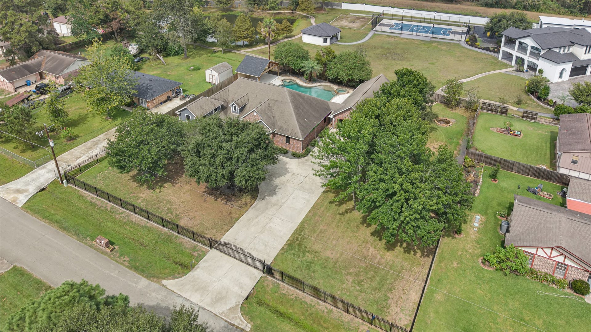 19763 Irenell Dr, Porter, TX 77365 Expansive property featuring a charming home with a spacious driveway, lush greenery, and a private pool, perfect for outdoor enjoyment and leisure.