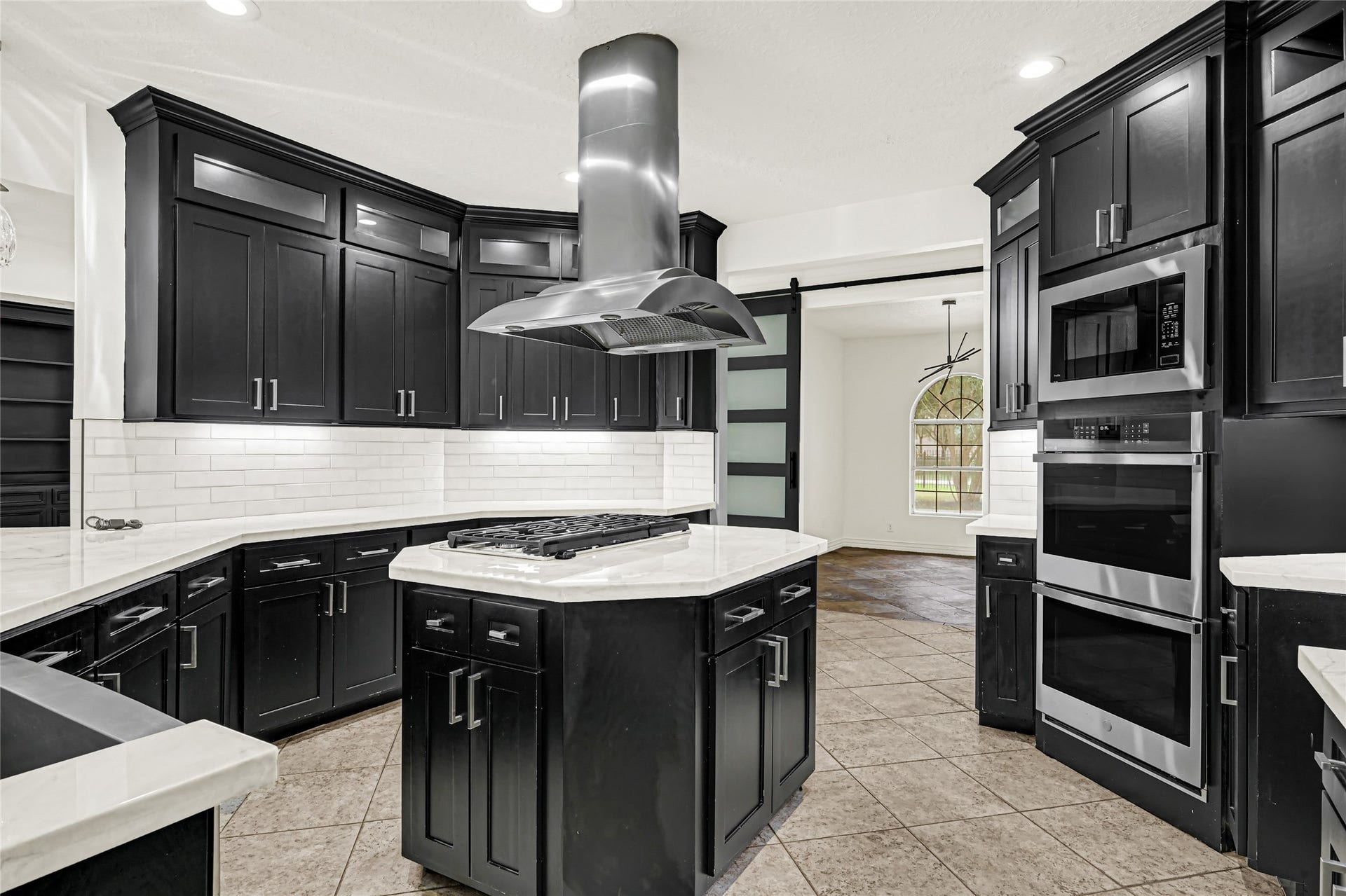 19763 Irenell Dr, Porter, TX 77365 Sleek modern kitchen with dark cabinetry, stainless steel appliances, and a central island with a stylish range hood, perfect for culinary enthusiasts.
