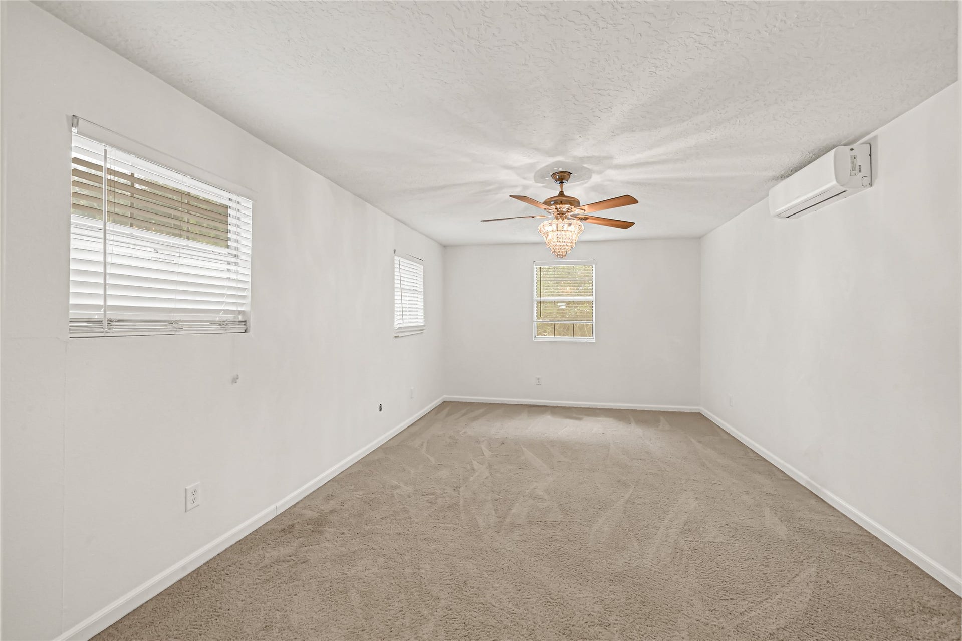 19763 Irenell Dr, Porter, TX 77365 Spacious room with soft carpeting, a decorative ceiling fan, and ample natural light from multiple windows, offering a comfortable and inviting atmosphere.