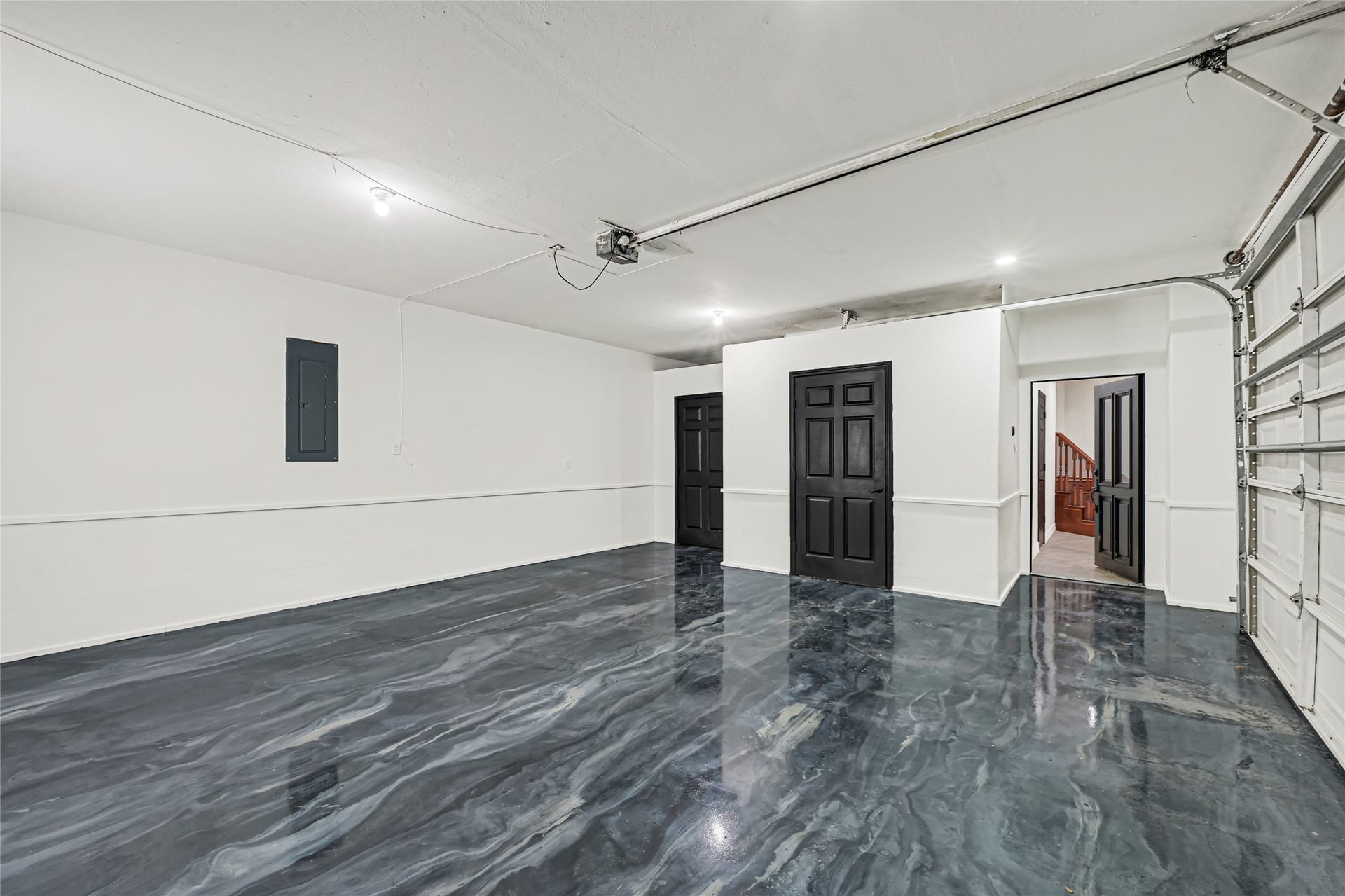 19763 Irenell Dr, Porter, TX 77365 Spacious and modern garage featuring sleek, polished flooring and a clean, bright interior with multiple access doors for convenience.