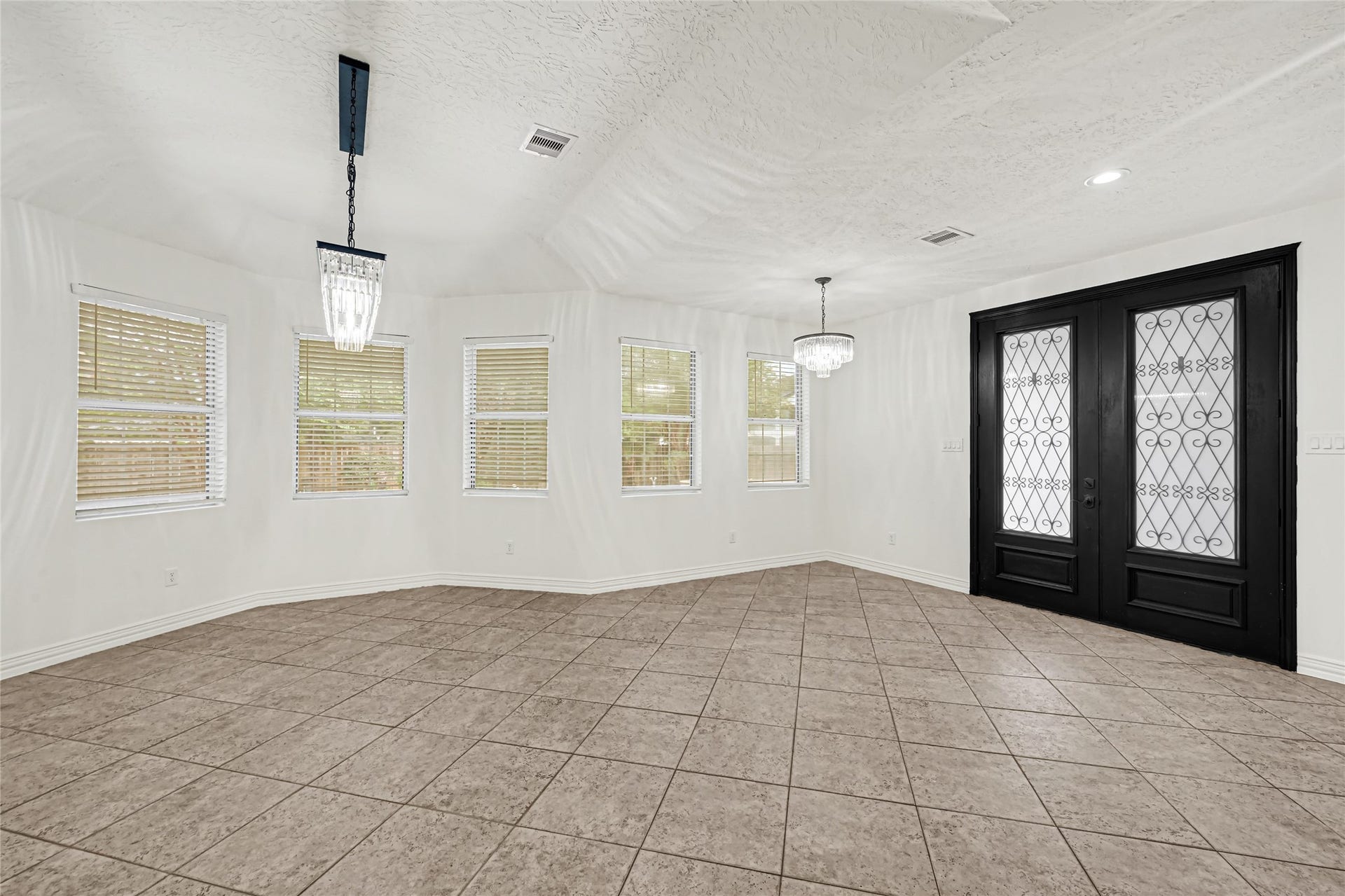 19763 Irenell Dr, Porter, TX 77365 Bright and spacious room featuring elegant tile flooring, abundant natural light from multiple windows, and striking double doors with intricate ironwork.