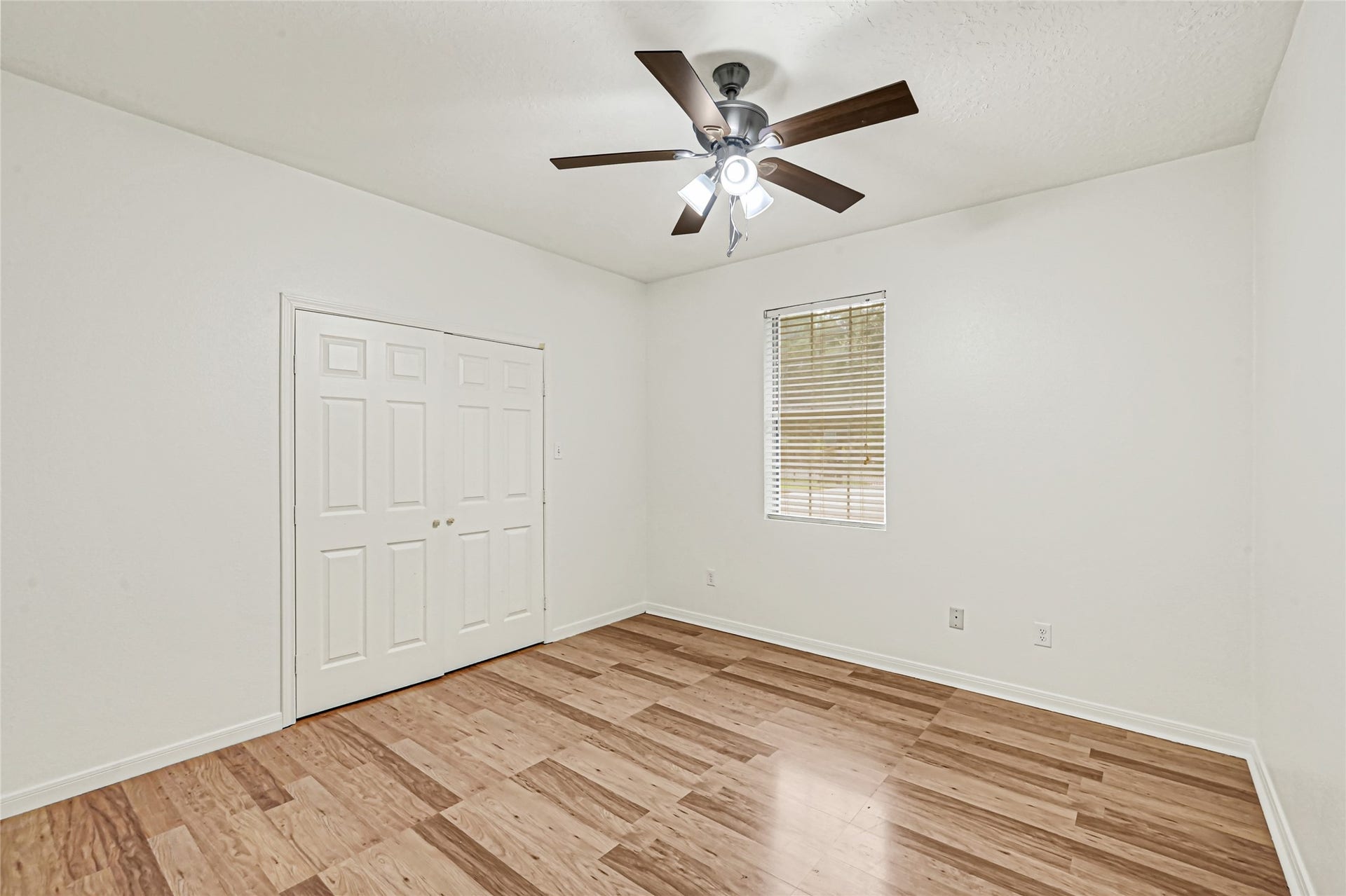 19763 Irenell Dr, Porter, TX 77365 Bright and airy bedroom featuring a ceiling fan, laminate wood flooring, and a spacious closet with double doors.
