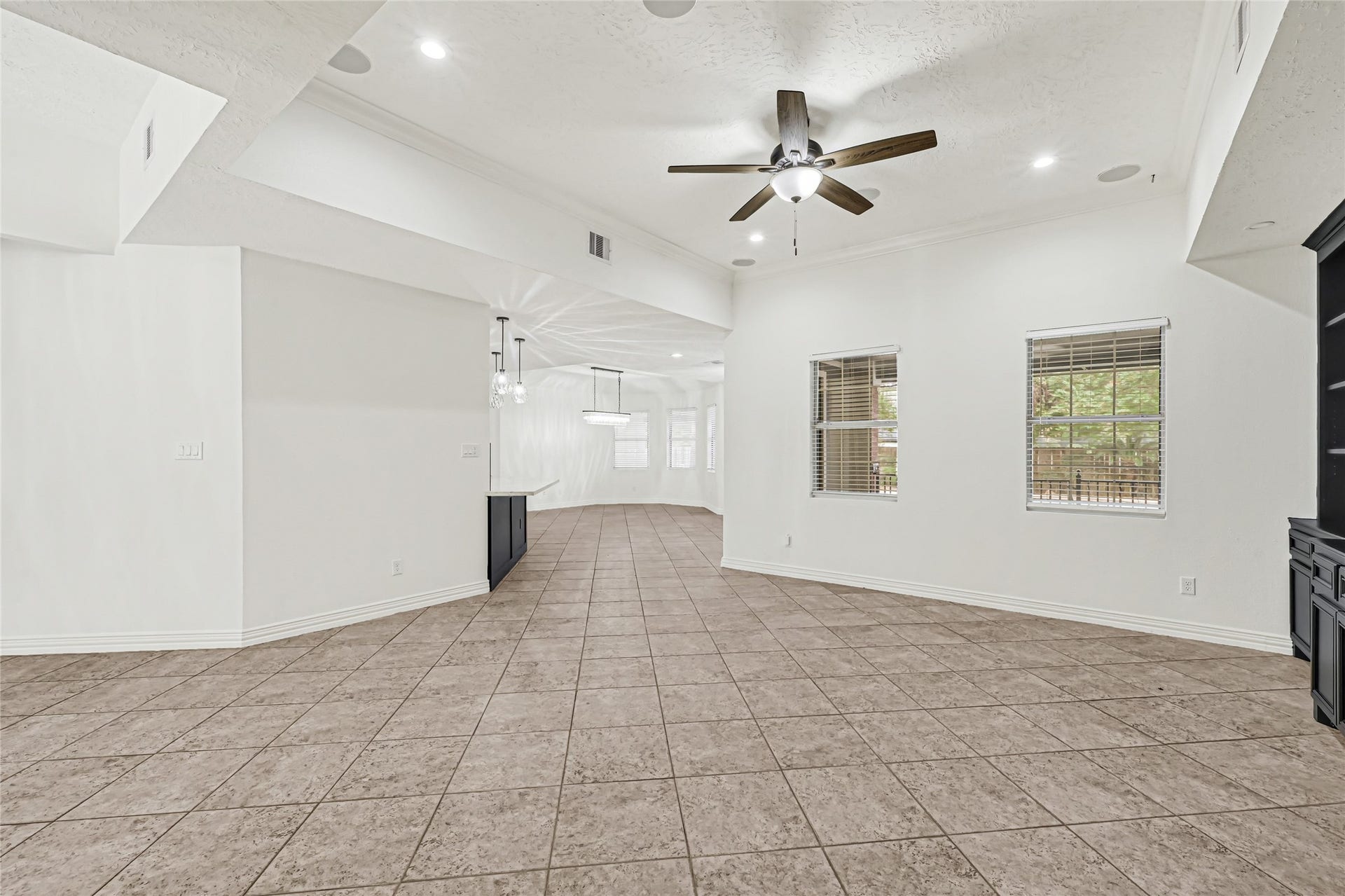 19763 Irenell Dr, Porter, TX 77365 Spacious open-concept living area with tile flooring, recessed lighting, and a ceiling fan, offering ample natural light through large windows.