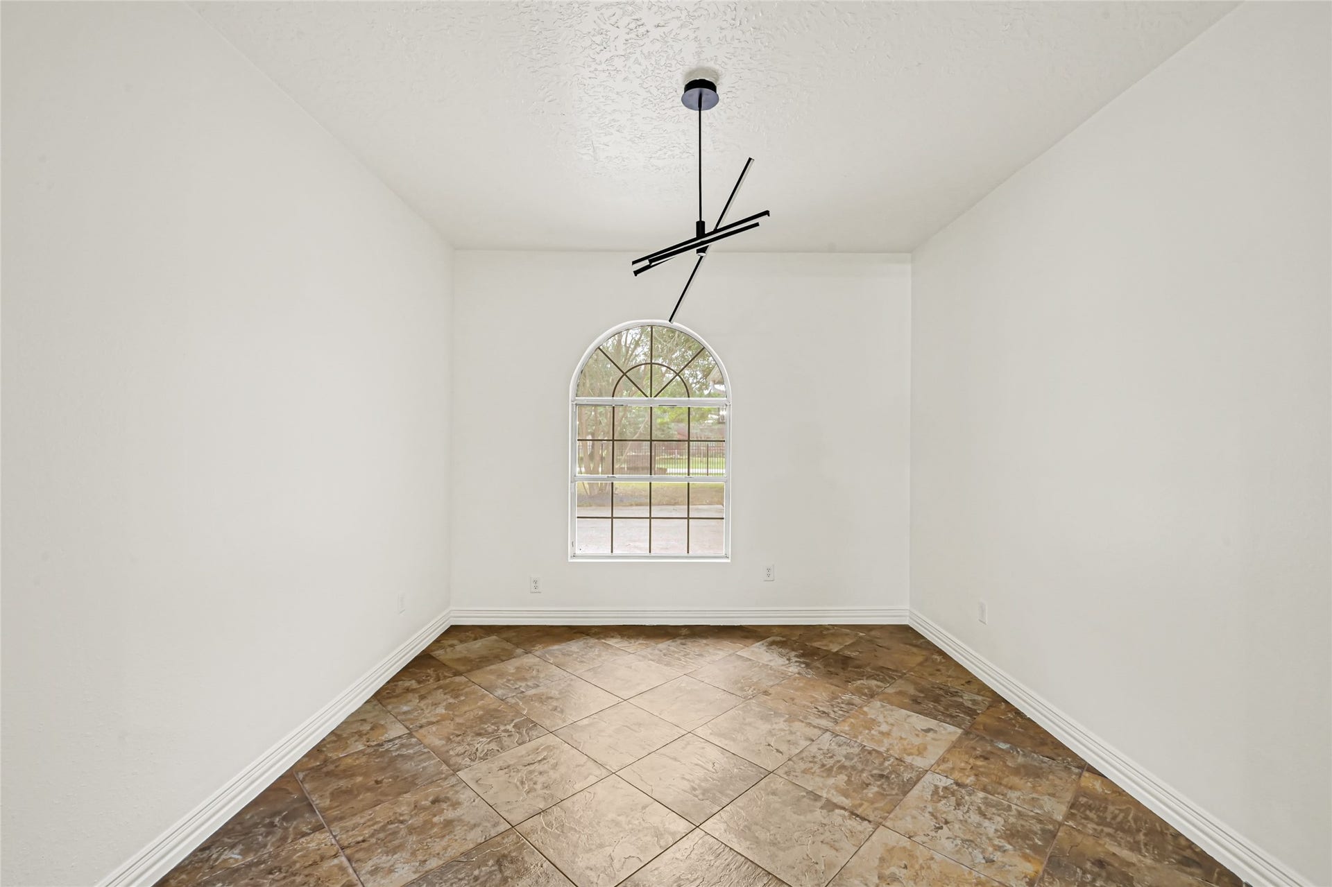 19763 Irenell Dr, Porter, TX 77365 Bright room with elegant tile flooring, an arched window offering natural light, and a modern ceiling light fixture.