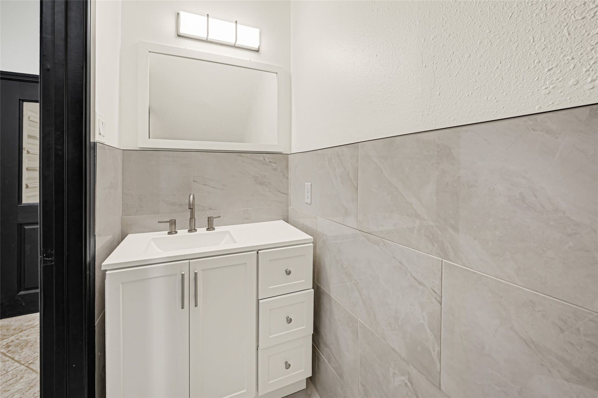 19763 Irenell Dr, Porter, TX 77365 Modern bathroom with a sleek white vanity, elegant gray tile backsplash, and contemporary lighting.