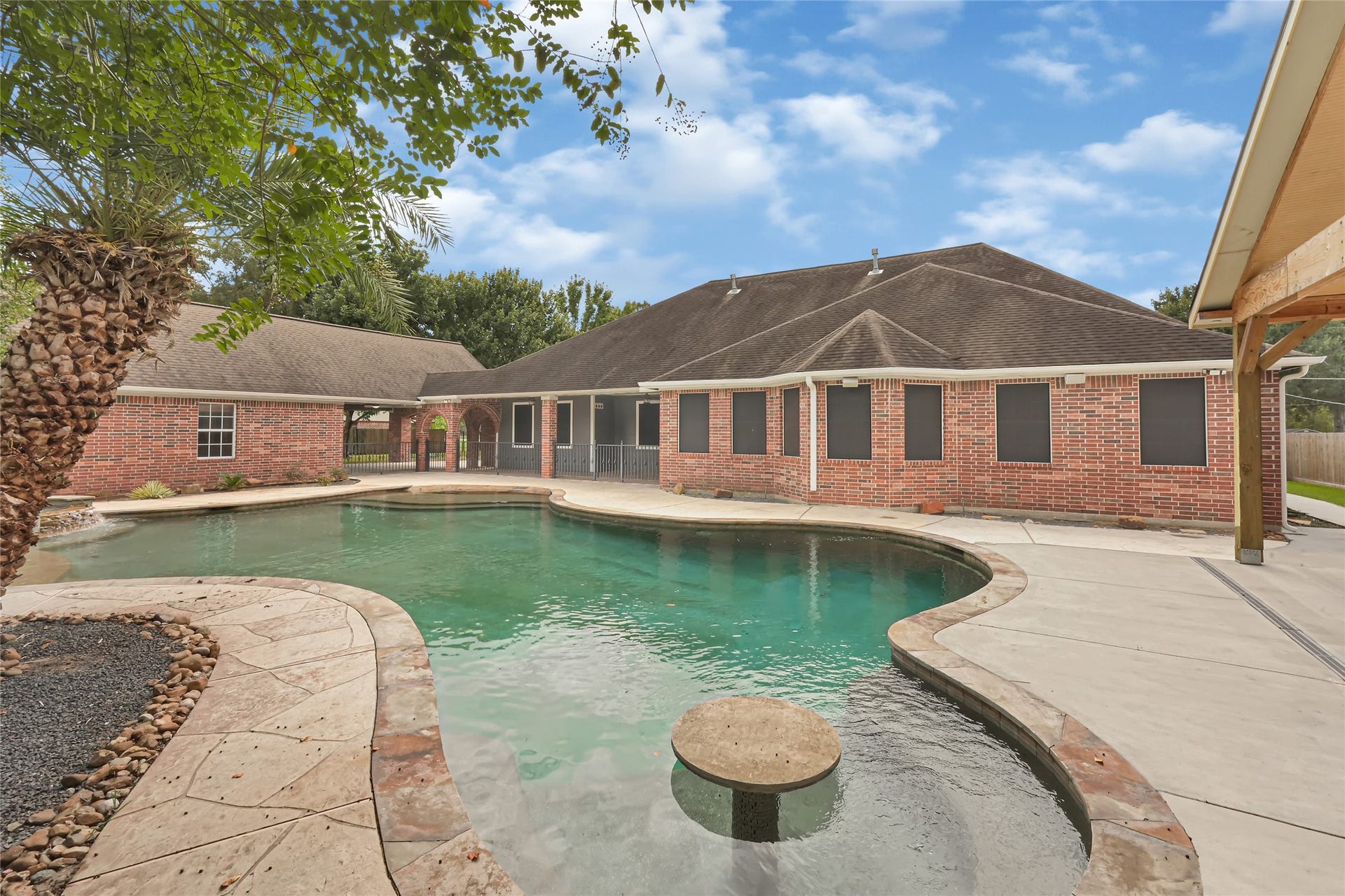 19763 Irenell Dr, Porter, TX 77365 Spacious backyard oasis featuring a large, inviting pool surrounded by elegant brick architecture and lush landscaping, perfect for relaxation and entertaining.