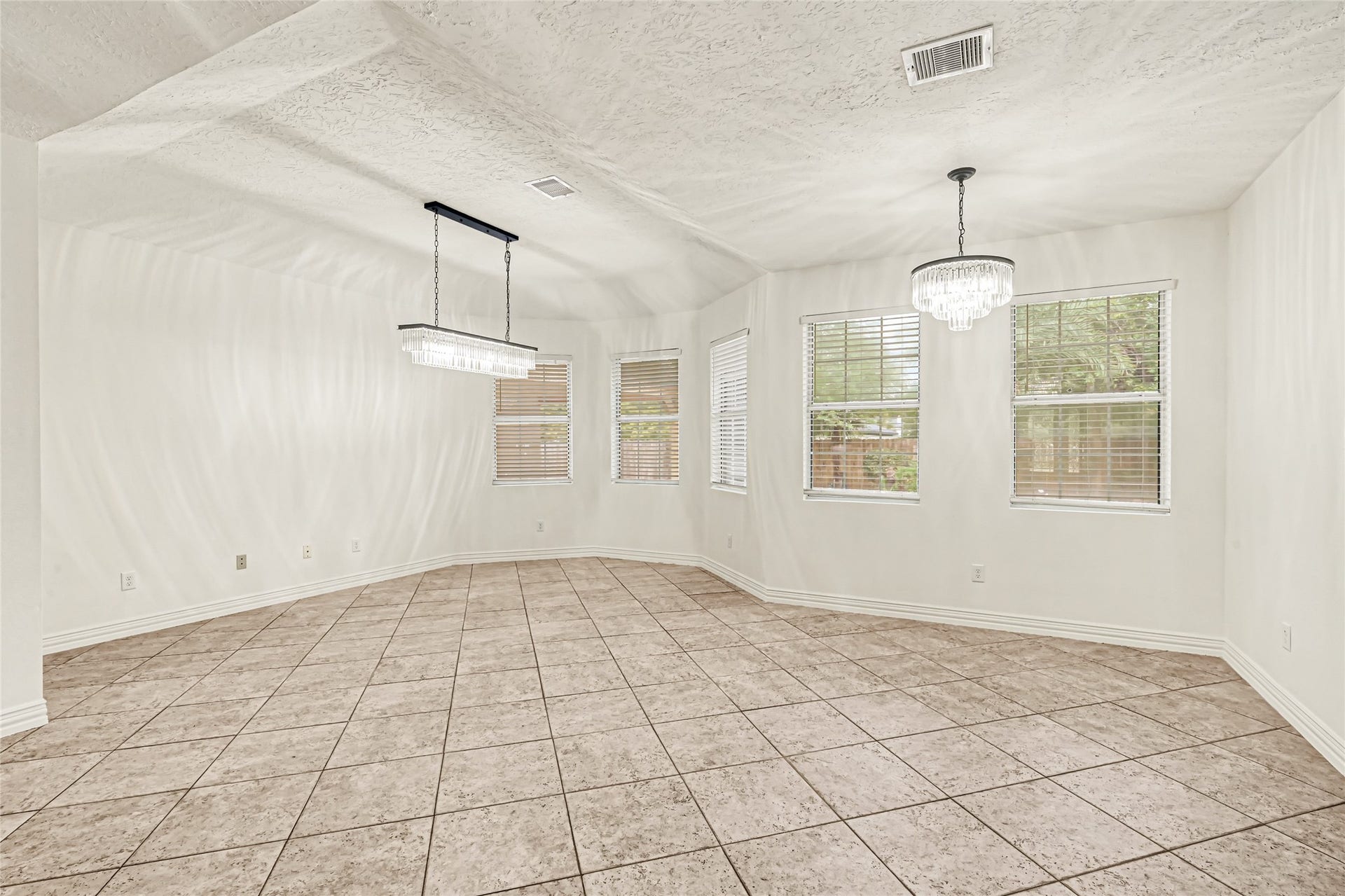 19763 Irenell Dr, Porter, TX 77365 Spacious dining area with elegant tile flooring, large windows for natural light, and stylish modern chandeliers.