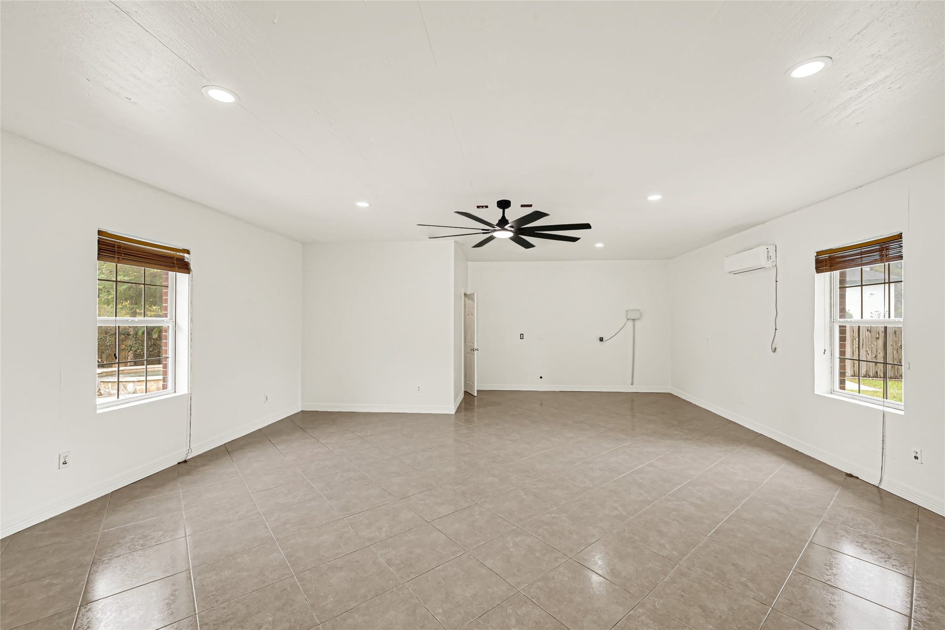19763 Irenell Dr, Porter, TX 77365 Spacious living area with sleek tile flooring, abundant natural light, and a modern ceiling fan, perfect for comfortable living and entertaining.