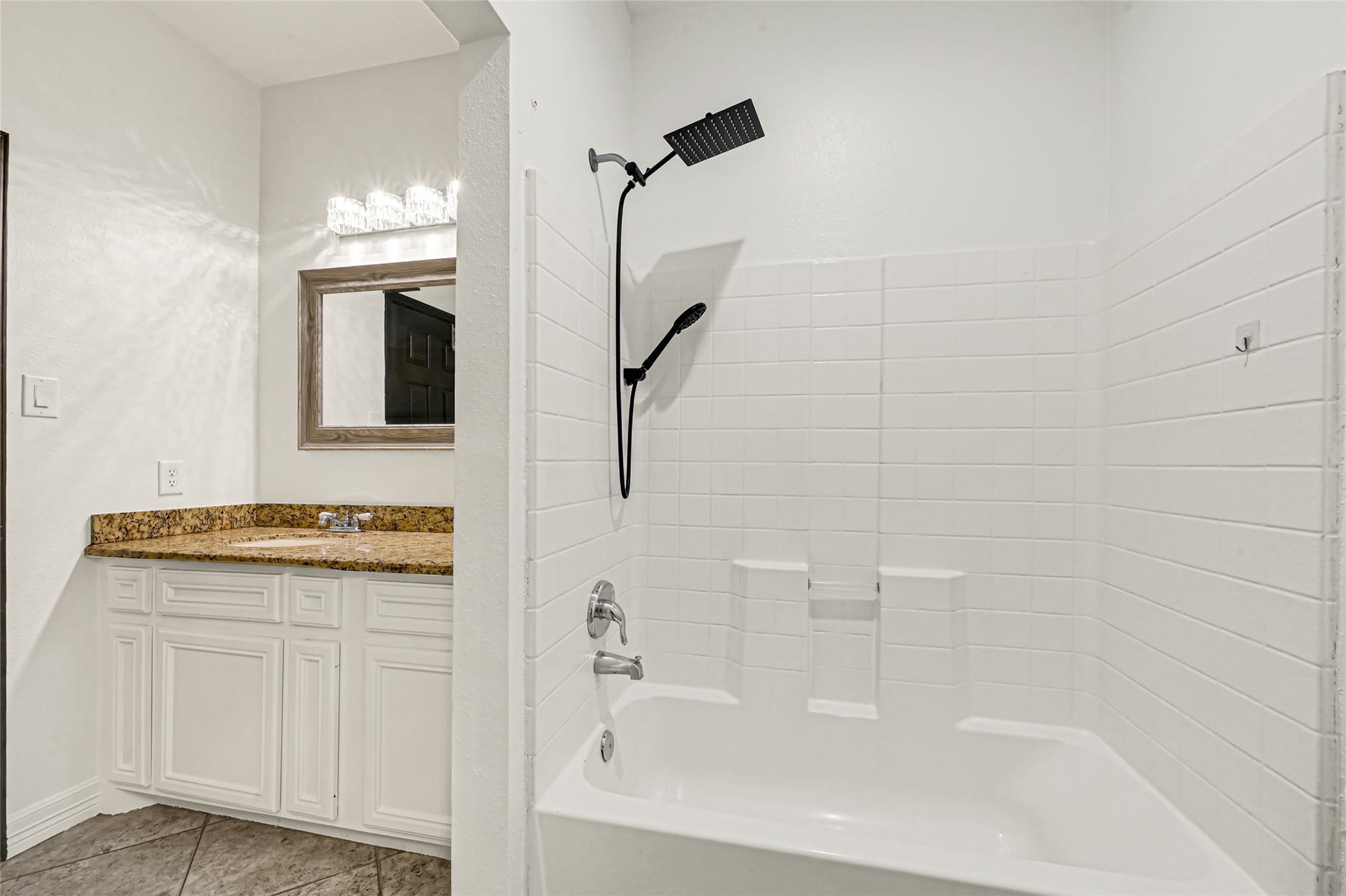 19763 Irenell Dr, Porter, TX 77365 Modern bathroom featuring a sleek shower-tub combo with white tile surround, complemented by a stylish granite countertop and elegant vanity.