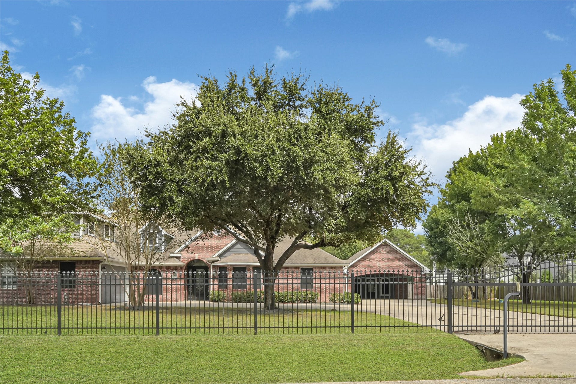 19763 Irenell Dr, Porter, TX 77365 Charming brick home with a spacious front yard, mature trees, and a gated driveway for added privacy.