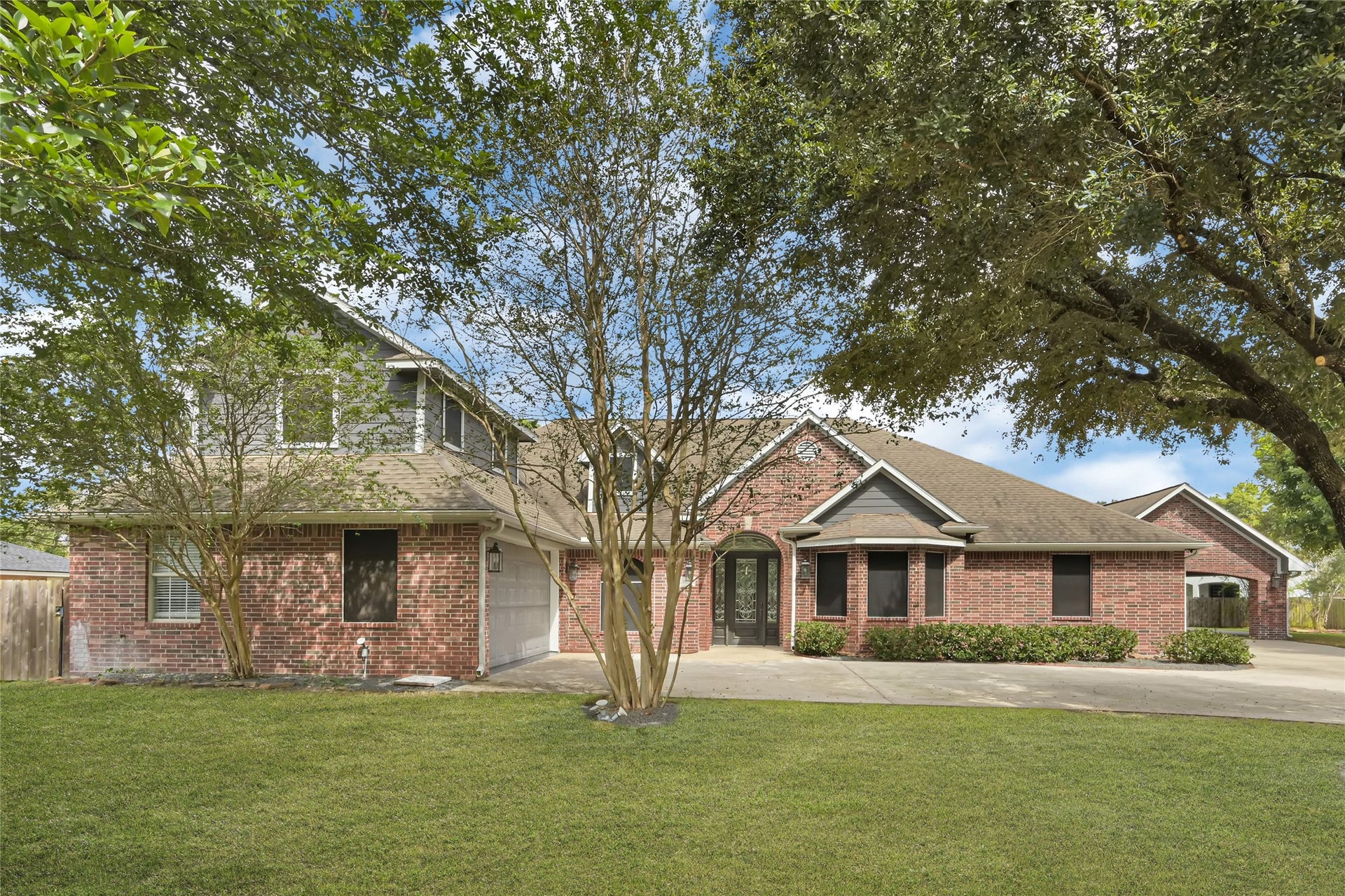 19763 Irenell Dr, Porter, TX 77365 Charming brick home with a welcoming front yard, mature trees, and a spacious driveway leading to an attached garage.