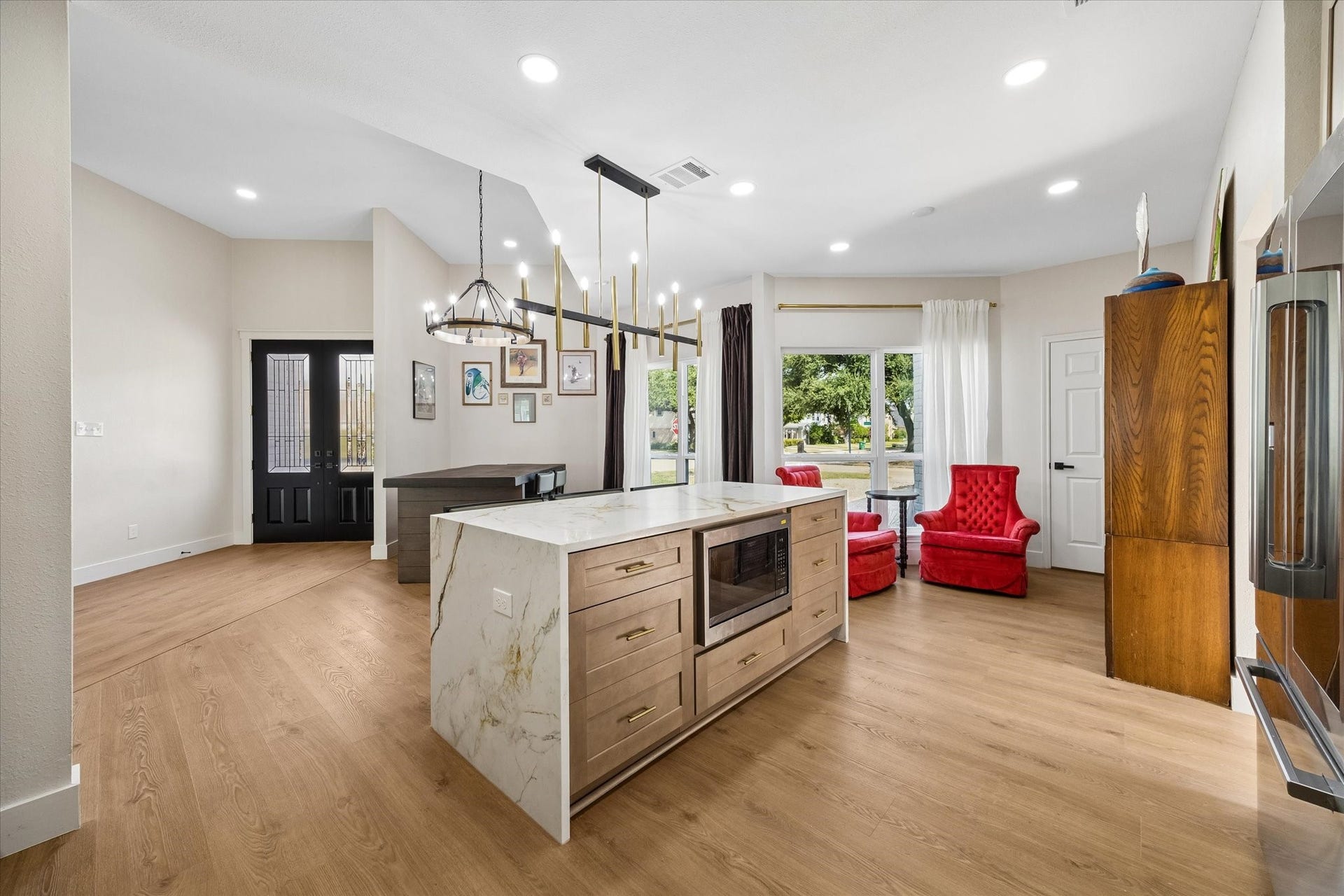 2302 Ashford Hollow Lane, Houston, TX 77077 Modern open-concept space featuring a sleek kitchen island, elegant lighting, and seating area by a large window, offering a warm and inviting atmosphere.