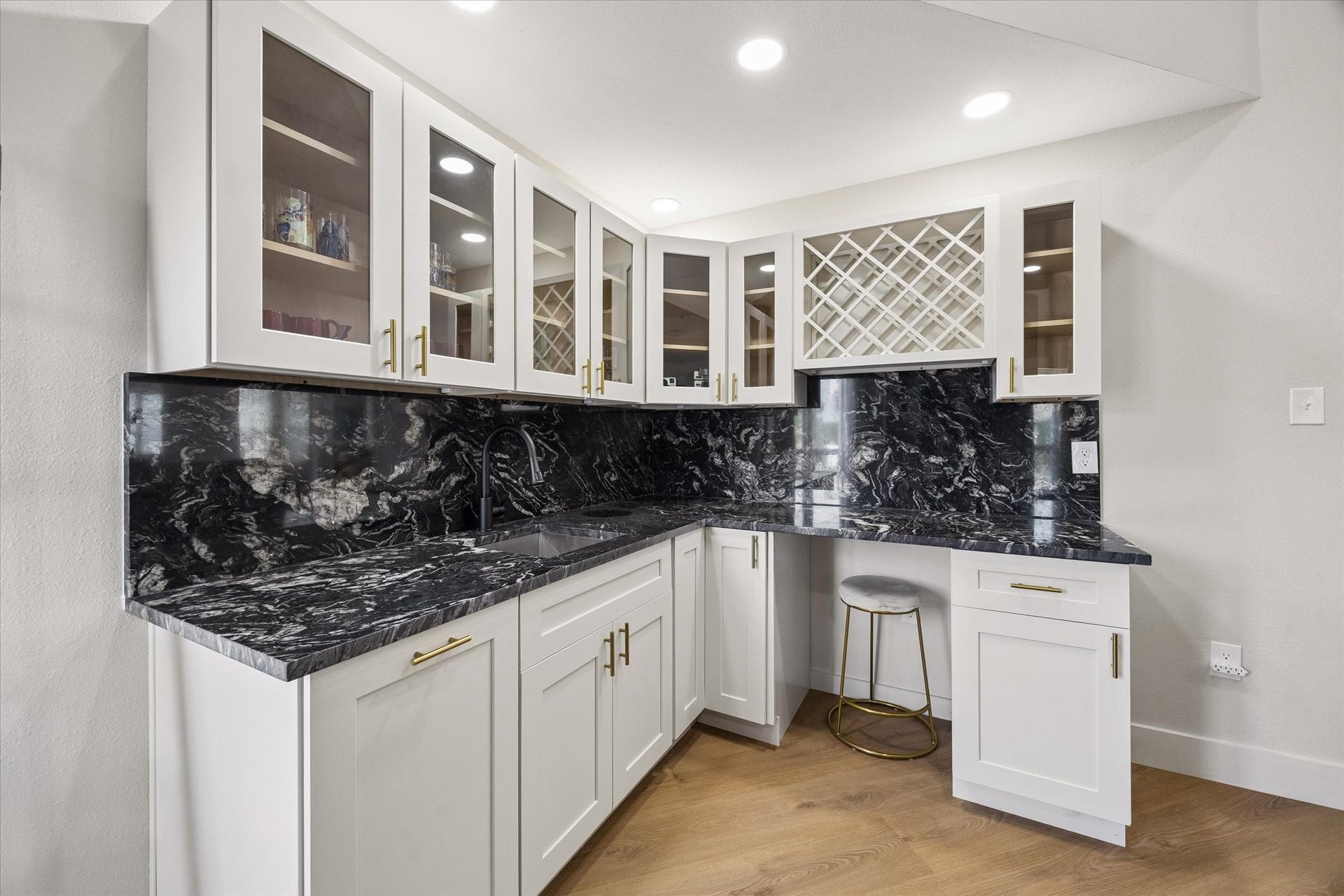 2302 Ashford Hollow Lane, Houston, TX 77077 This elegant wet bar flows into the living room area and features sleek black countertops, white cabinetry with glass doors, and a built-in wine rack. It is perfect for entertaining.
