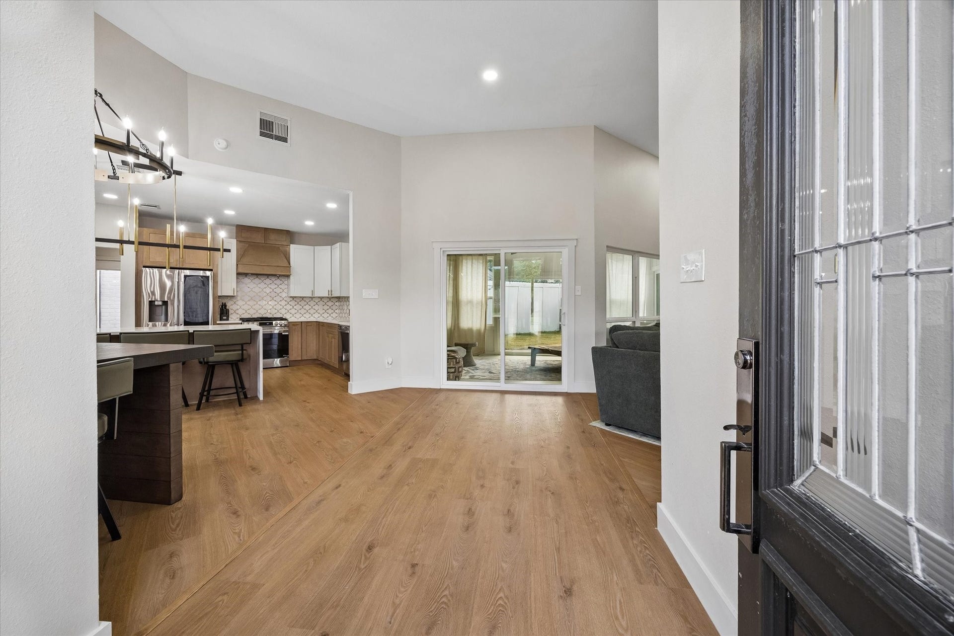 2302 Ashford Hollow Lane, Houston, TX 77077 Step into a modern open-concept living area featuring sleek hardwood floors, a stylish kitchen with stainless steel appliances, and a cozy living space enhanced by natural light streaming through large windows.