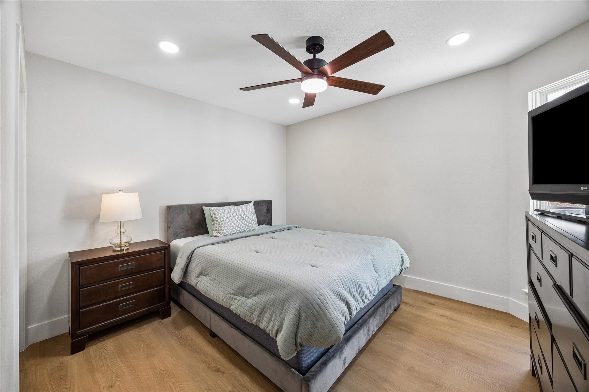 2302 Ashford Hollow Lane, Houston, TX 77077 This cozy secondary bedroom features a modern ceiling fan, sleek wood looking floors, and ample natural light from a corner window.