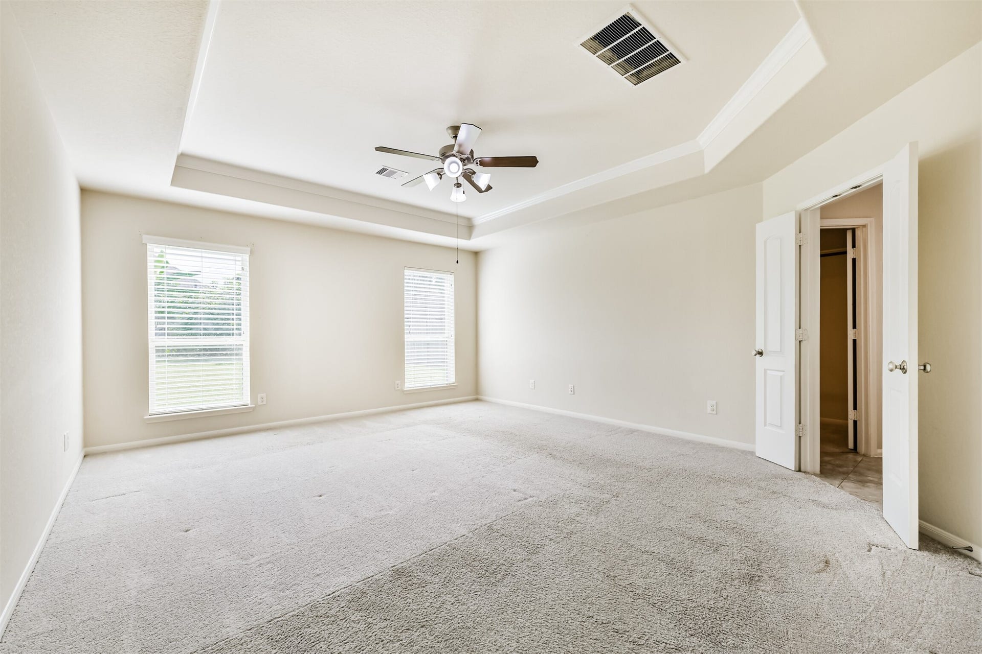 2811 Afton Drive, Pearland, TX 77581 Spacious primary bedroom featuring abundant natural light, elegant tray ceiling, and plush carpeting for ultimate comfort.
