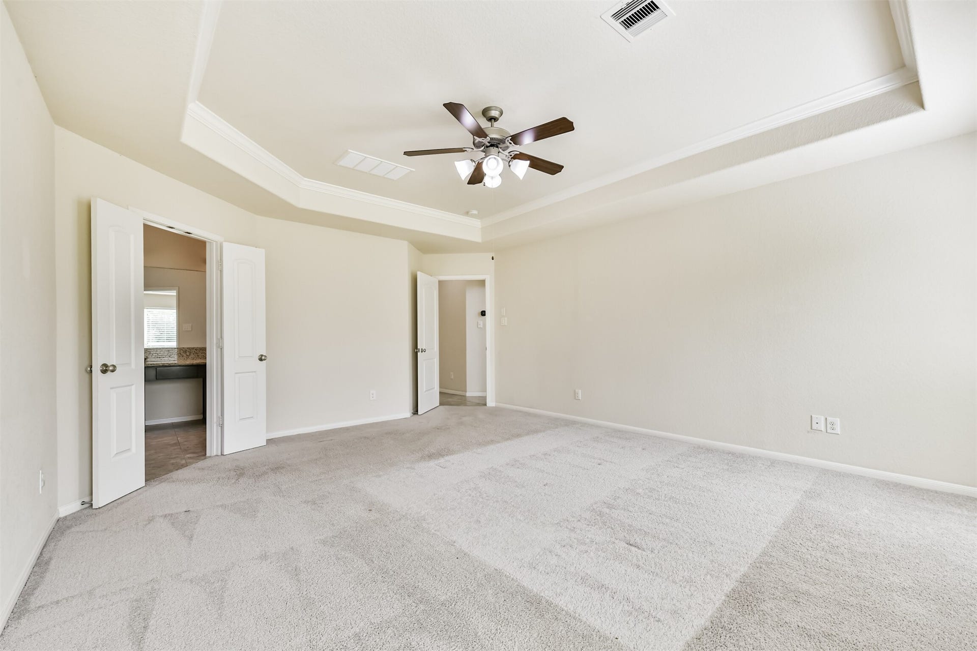 2811 Afton Drive, Pearland, TX 77581 Spacious primary bedroom with elegant tray ceiling, plush carpeting, and an en-suite bathroom for ultimate comfort and convenience.