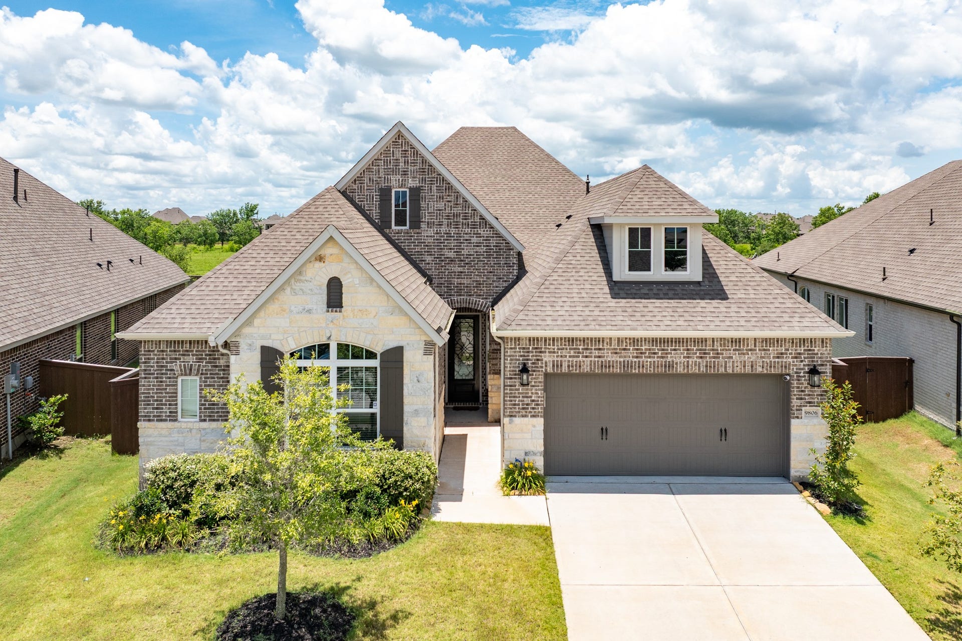 9806 Starry Night Lane, Manvel, TX 77578 Elevated exterior featuring a sophisticated blend of brick and stone masonry, complemented by professional, meticulously maintained landscaping that enhances the property's curb appeal.