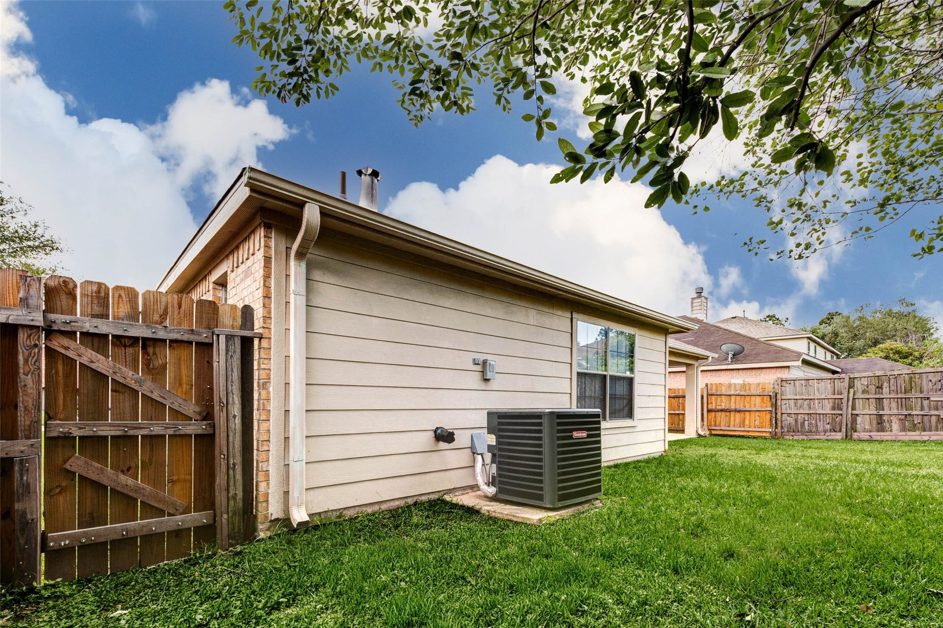 21211 Arcadia Park Lane, Humble, TX 77338 Side yard view showcasing the homes exterior construction and HVAC system placement for easy maintenance access. The fenced perimeter enhances privacy and security, while the open grassy area provides additional outdoor space. A practical layout that supports both functionality and low-maintenance living.