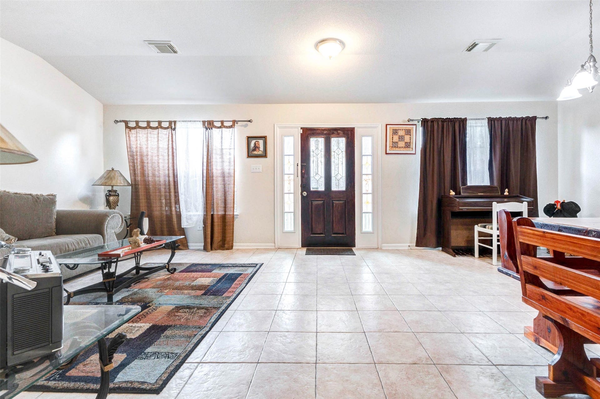 21211 Arcadia Park Lane, Humble, TX 77338 Bright and welcoming entry and living space featuring a wide-open layout with tile flooring and abundant natural light. The front door is framed by sidelights and large windows, creating a warm first impression. The layout offers flexibility for both seating and dining areas, while neutral tones and clean lines provide a timeless backdrop ideal for everyday living and entertaining guests.