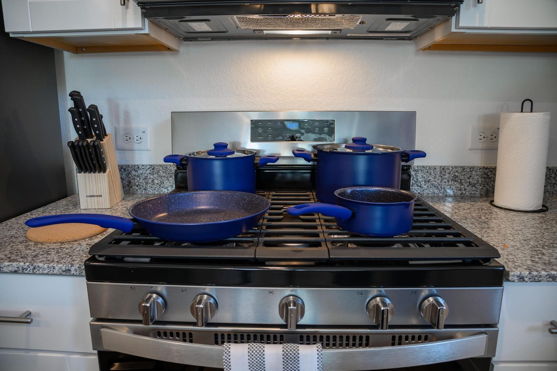 1301 Bright Hill Drive, Katy, TX 77493 Modern kitchen with a sleek stainless steel gas stove, complemented by blue cookware and granite countertops, offering a stylish and functional cooking space.