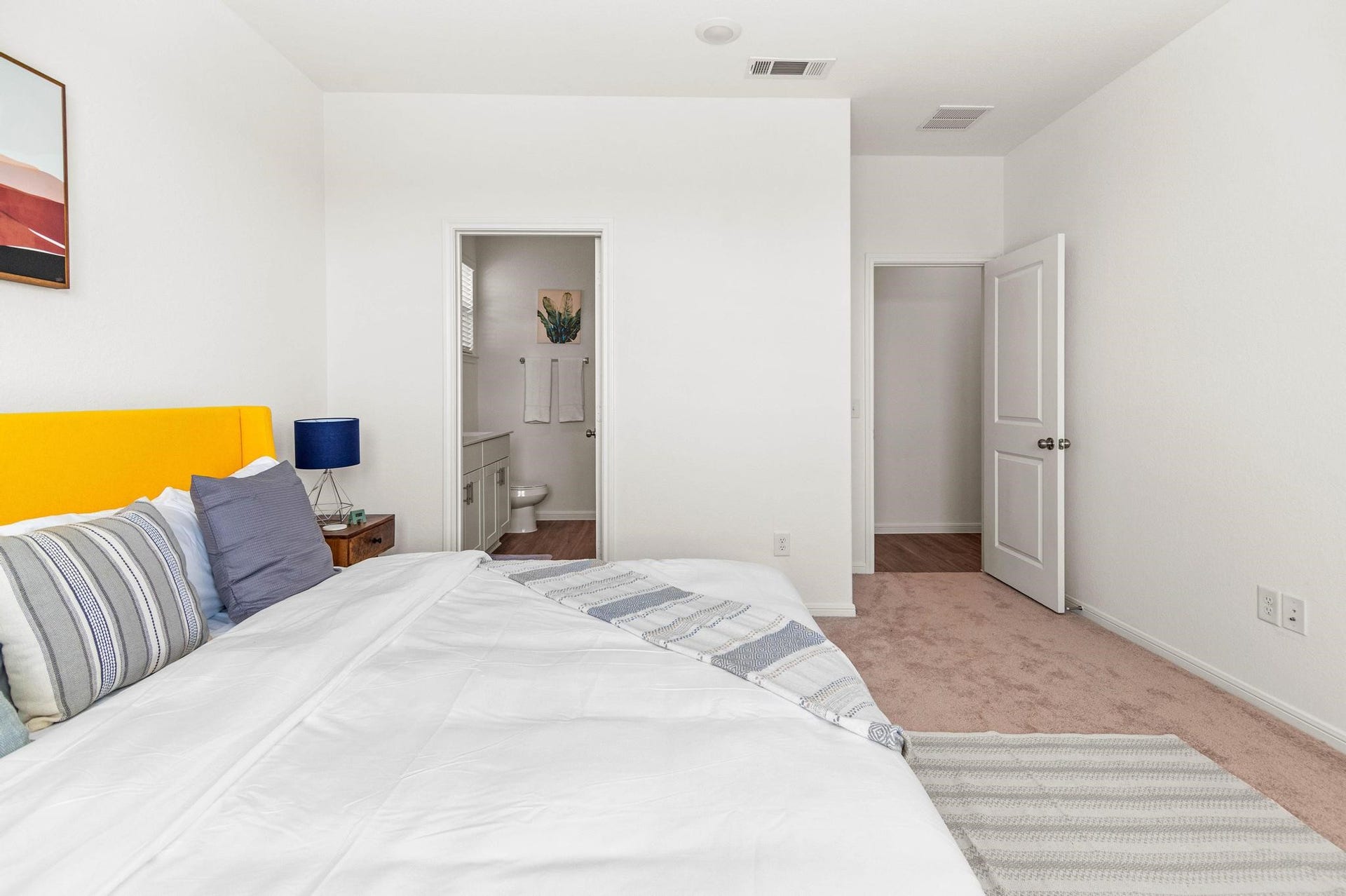 1301 Bright Hill Drive, Katy, TX 77493 Bright and inviting bedroom featuring a cozy bed with a vibrant yellow headboard, plush carpeting, and convenient access to an en-suite bathroom.