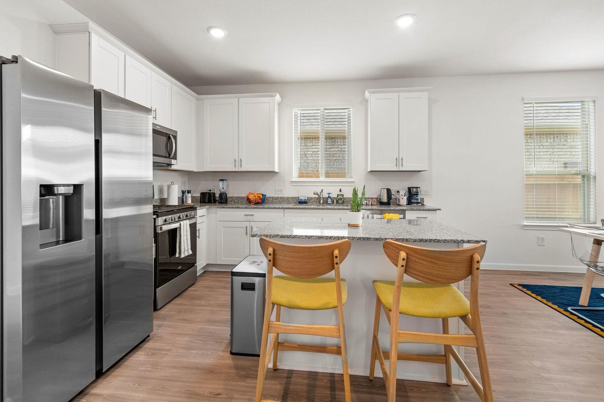 1301 Bright Hill Drive, Katy, TX 77493 Modern kitchen with sleek stainless steel appliances, white cabinetry, and a spacious granite island featuring stylish bar seating.