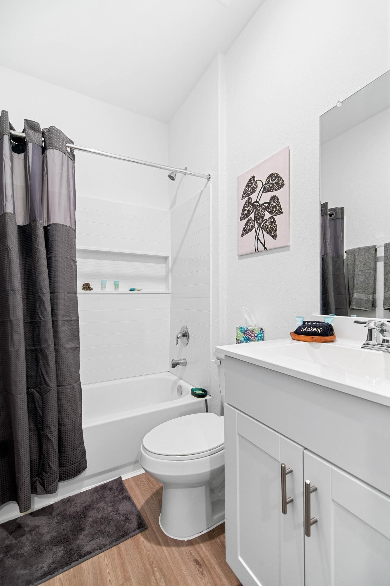 1301 Bright Hill Drive, Katy, TX 77493 Modern bathroom featuring a sleek vanity with ample storage, a full bathtub with a stylish shower curtain, and elegant wood flooring, all complemented by tasteful decor.