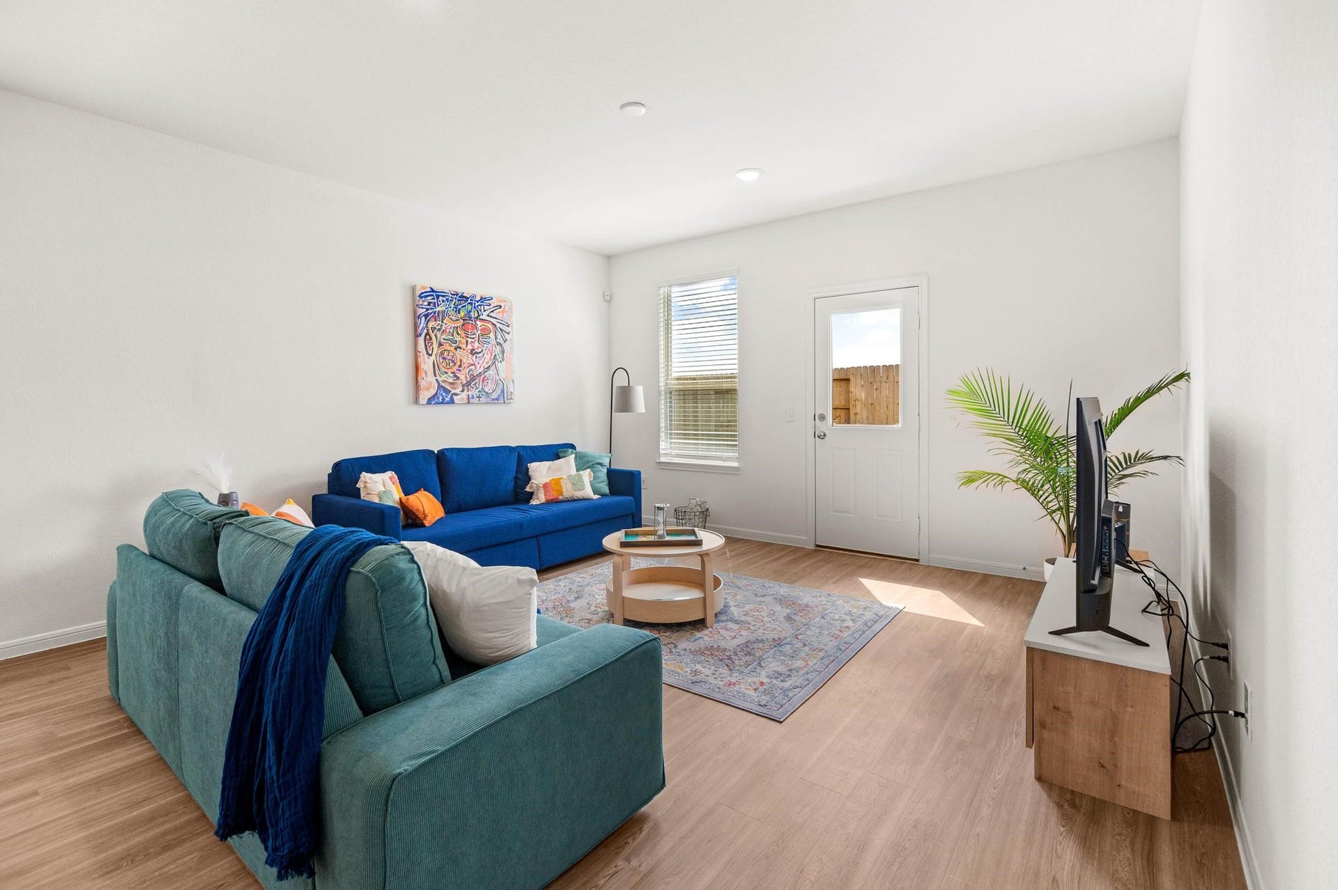 1301 Bright Hill Drive, Katy, TX 77493 Bright and inviting living room with modern furnishings, featuring a cozy blue sofa, stylish decor, and ample natural light from a large window and door.