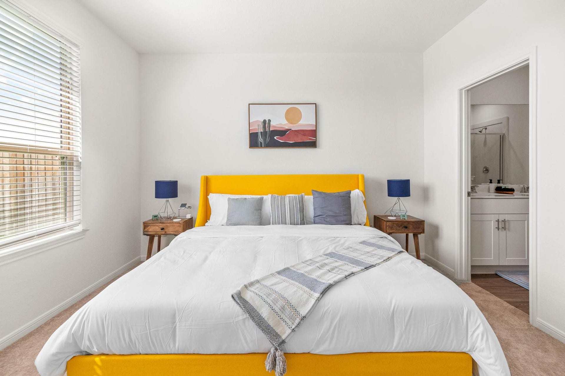 1301 Bright Hill Drive, Katy, TX 77493 Bright and inviting bedroom featuring a bold yellow bed frame, stylish side tables with modern lamps, and direct access to an en-suite bathroom.