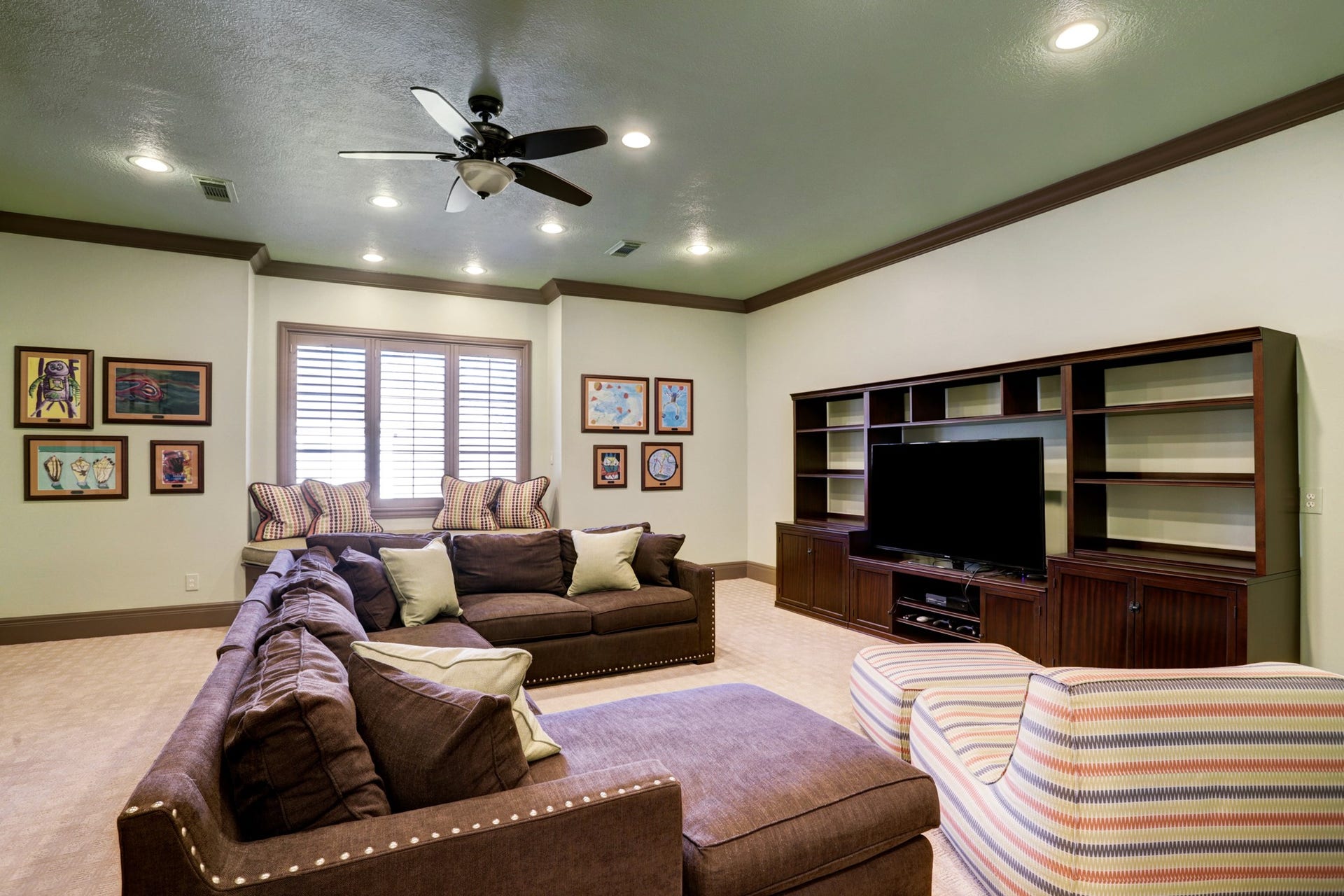 36 Saddlebrook Court, Tomball, TX 77375 The secondary living space boasts elegant, stained plantation shutters, intricate crown molding, and tasteful recessed lighting. It's the perfect area to unwind and entertain guests in style.