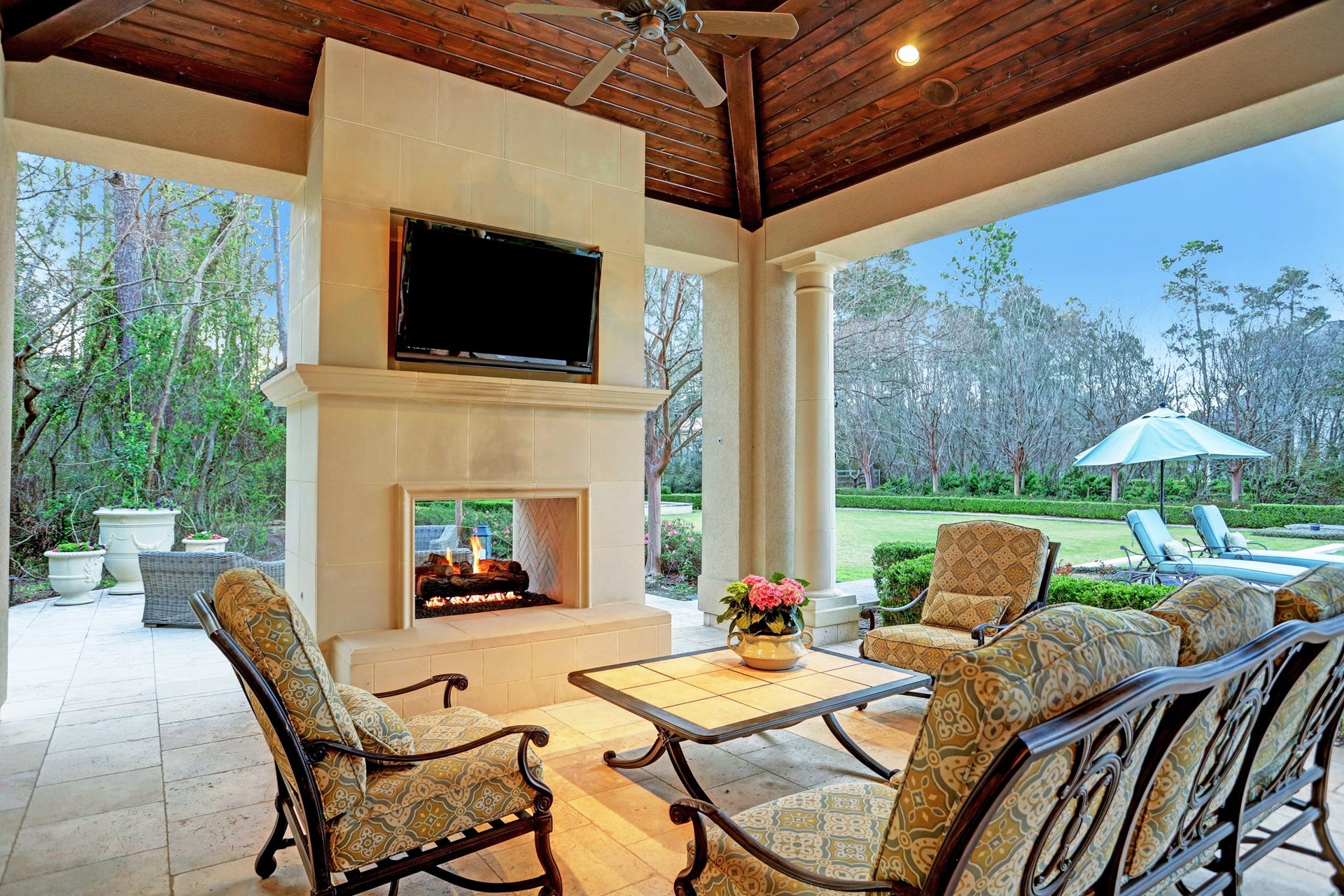 36 Saddlebrook Court, Tomball, TX 77375 The veranda off the pool house features travertine flooring, a cozy fireplace ambiance, and outdoor seating, providing the perfect setting to admire the stunningly curated grounds and breathtaking views.