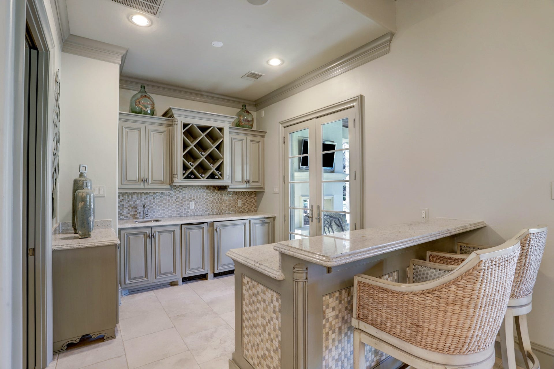 36 Saddlebrook Court, Tomball, TX 77375 Indulge in the luxurious guest/pool house featuring a wet bar with built-in beverage storage, granite countertops, tile backsplash, bar seating, and seamless access to the veranda, ideal for entertaining and relaxation.